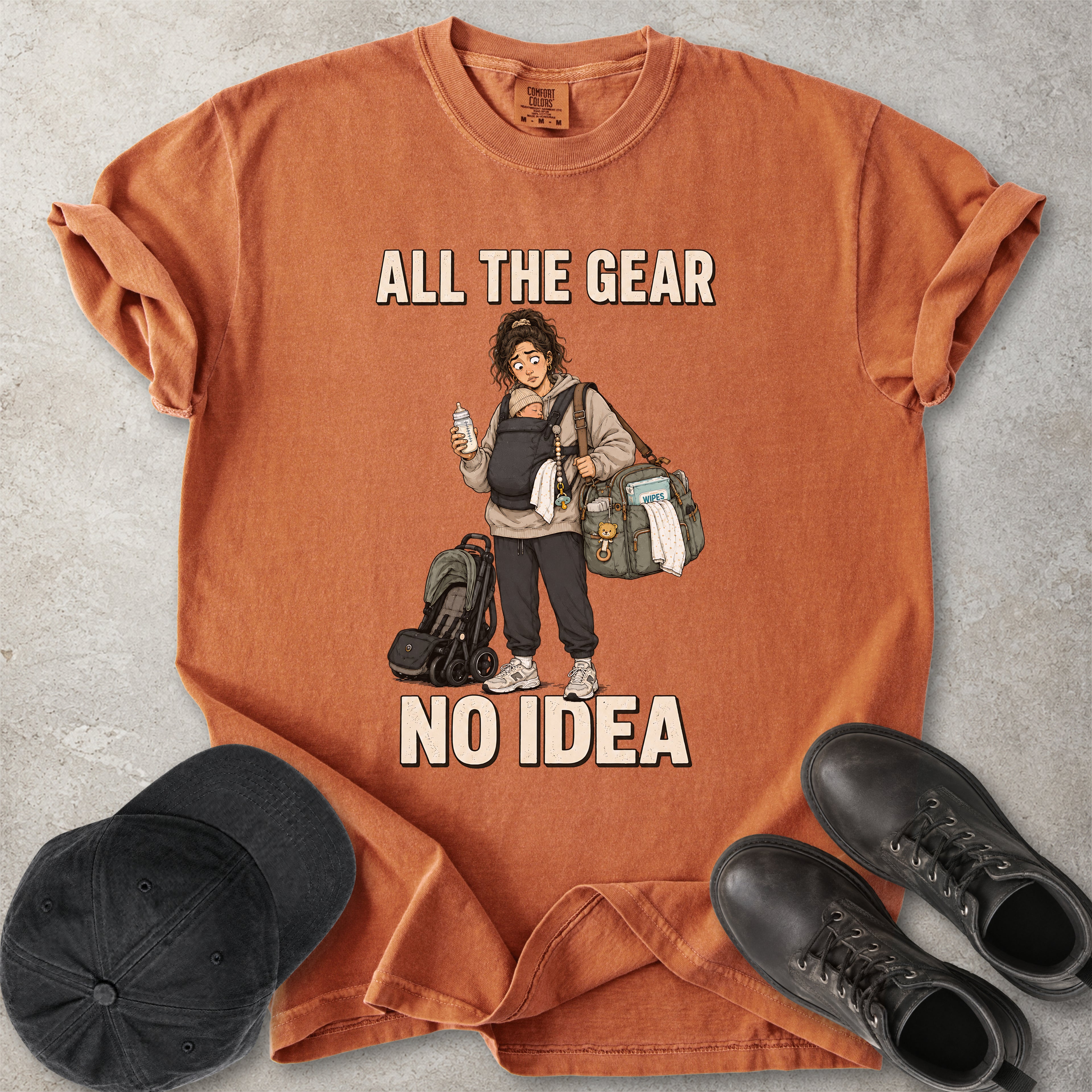Orange yam Comfort Colors 1717 T-shirt with a funny All the Gear No Idea new mum graphic showing a tired mother carrying a baby, bottle, changing bag and stroller.