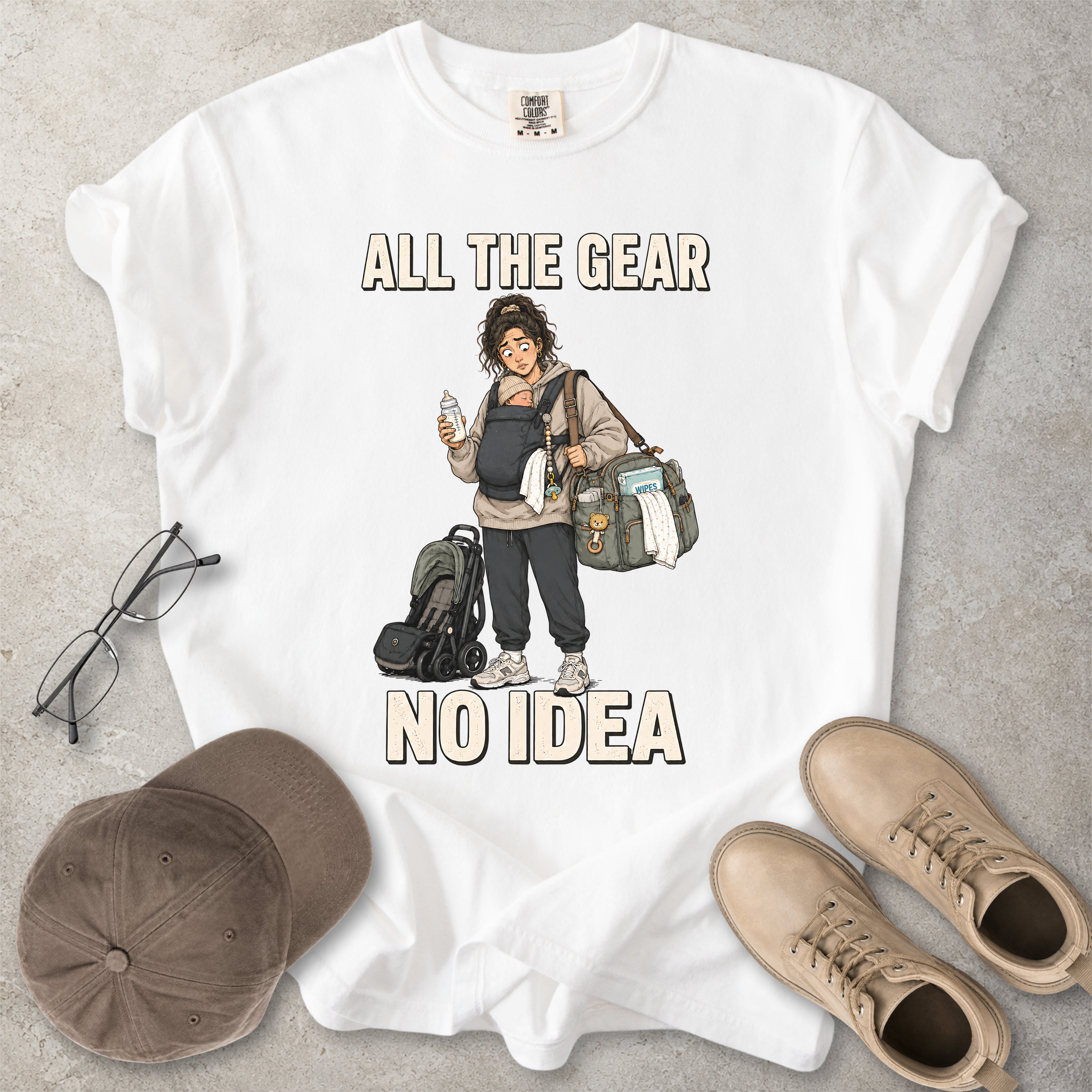 White Comfort Colors 1717 T-shirt with a funny All the Gear No Idea new mum graphic showing a tired mother carrying a baby, bottle, changing bag and stroller.