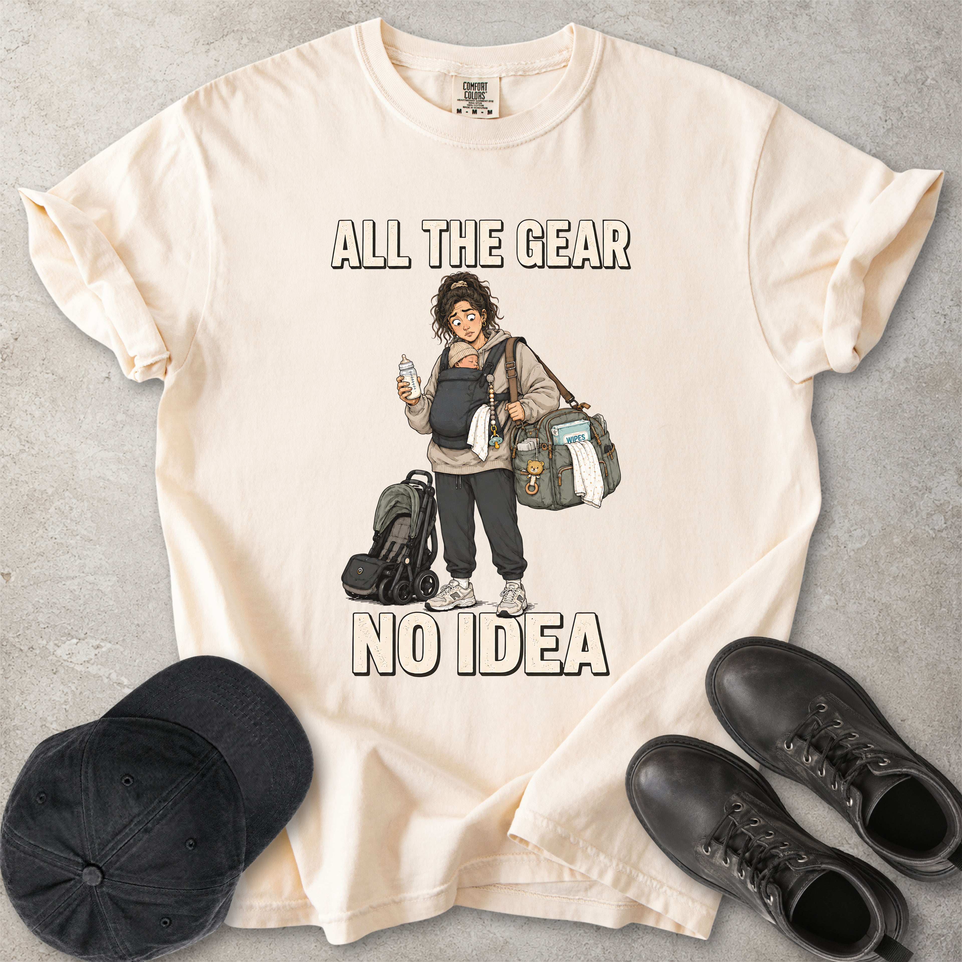 Ivory beige Comfort Colors 1717 T-shirt with a funny All the Gear No Idea new mum graphic showing a tired mother carrying a baby, bottle, changing bag and stroller.