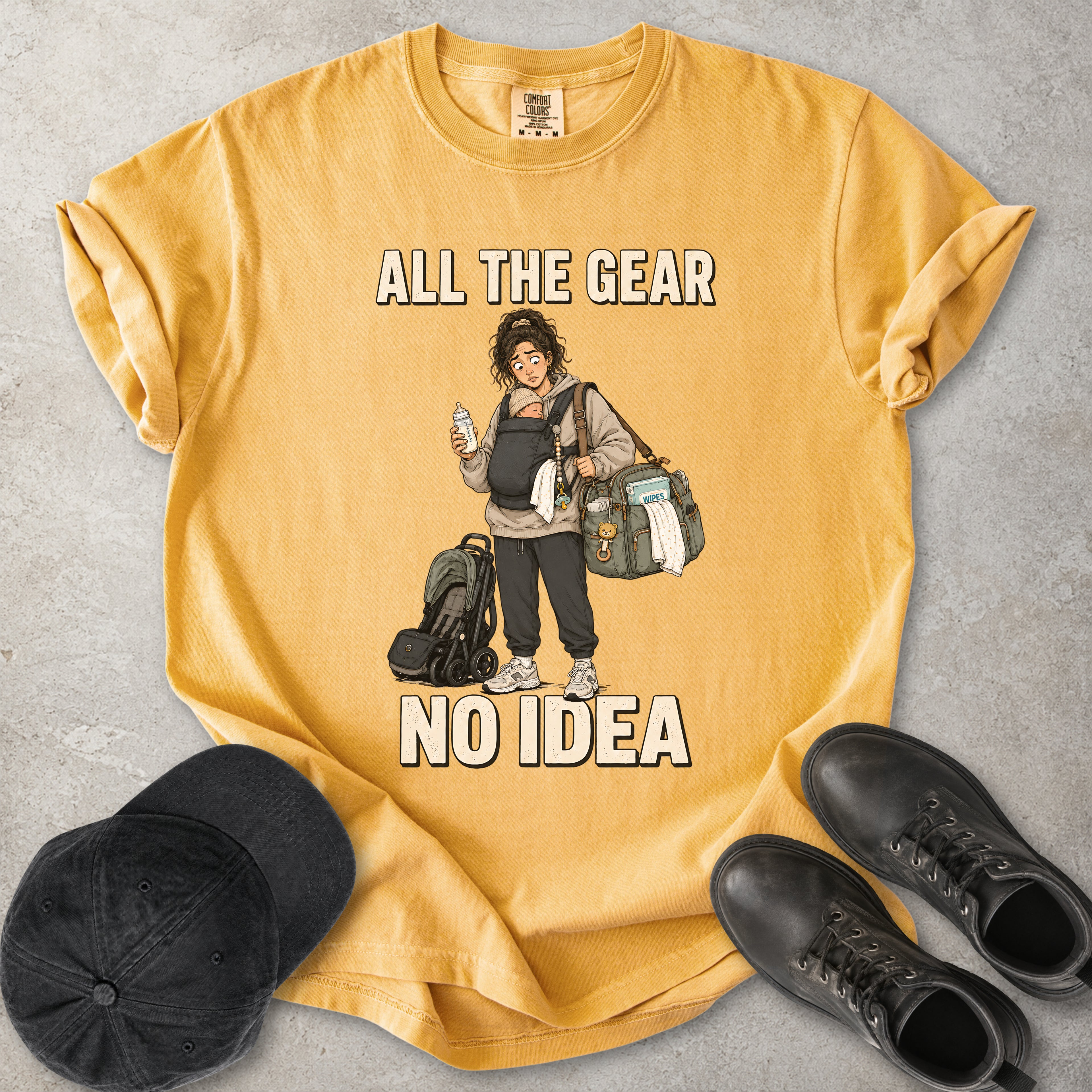 Mustard yellow Comfort Colors 1717 T-shirt with a funny All the Gear No Idea new mum graphic showing a tired mother carrying a baby, bottle, changing bag and stroller.