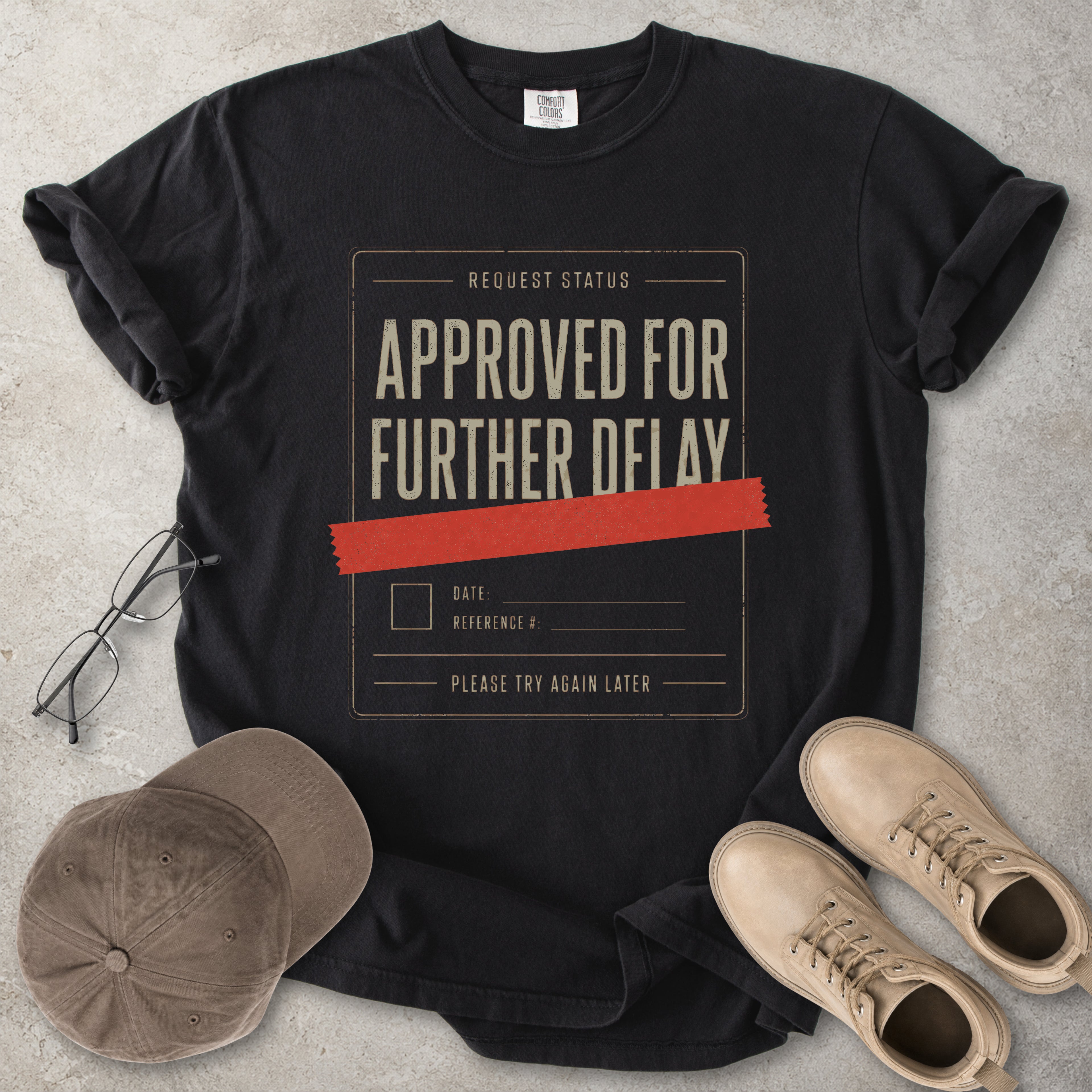 Black Comfort Colors 1717 T-shirt with a funny Approved for Further Delay graphic showing a request status form covered with red tape.