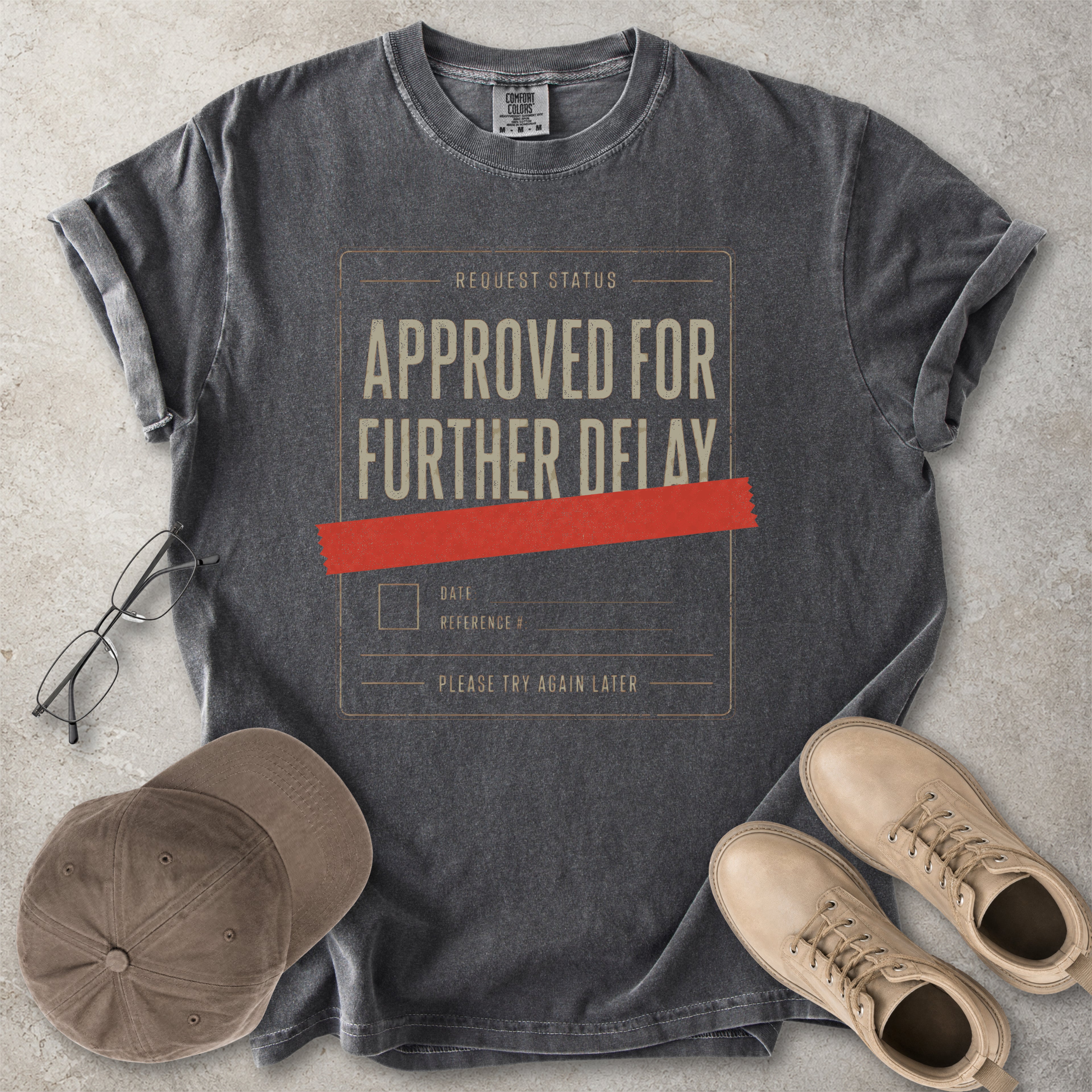 Pepper grey Comfort Colors 1717 T-shirt with a funny Approved for Further Delay graphic showing a request status form covered with red tape.