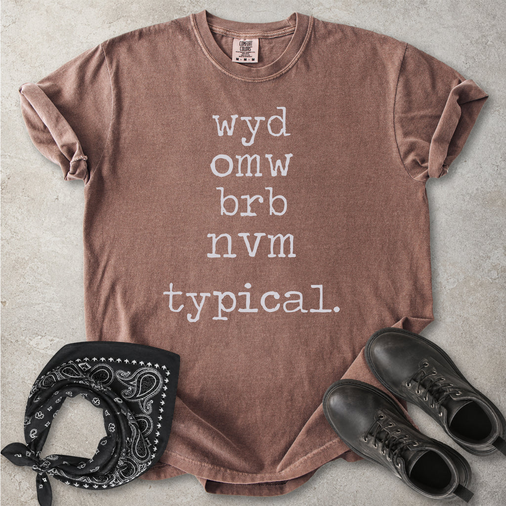 Espresso brown Comfort Colors graphic T-shirt with black text reading wyd omw brb nvm typical, styled with black boots and a black bandana