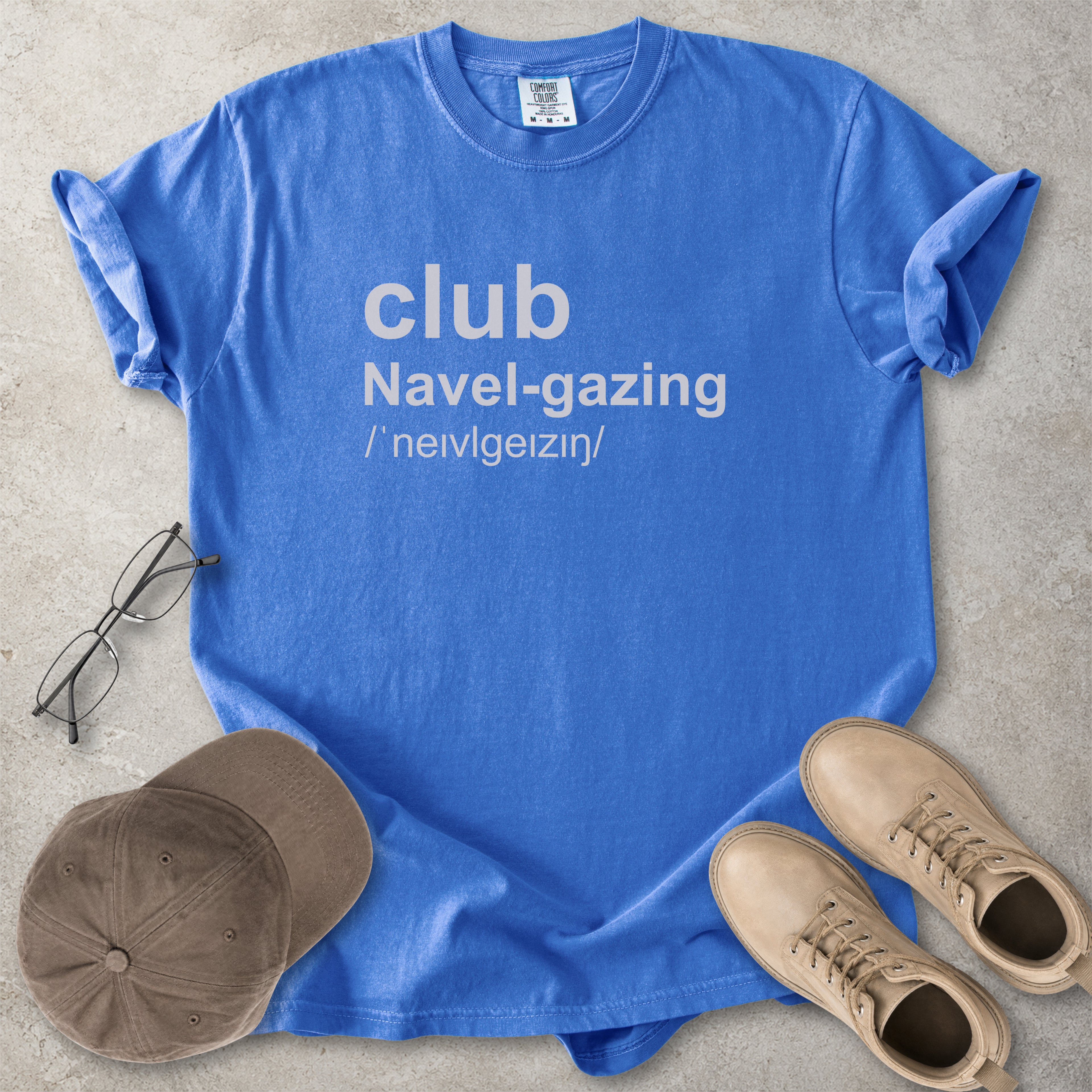 Flo blue Comfort Colors graphic T-shirt with grey text reading club navel-gazing, styled with notebook, pen, glasses and tan boots