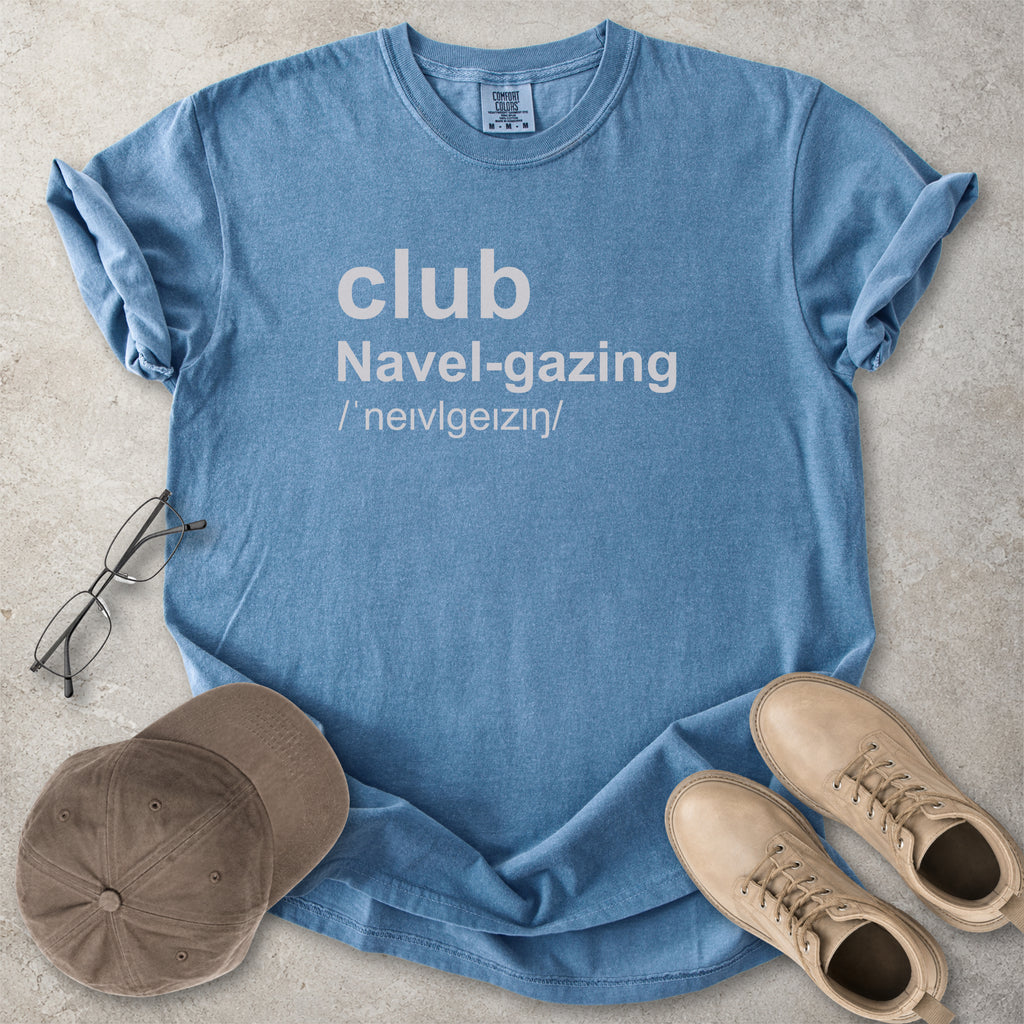 Blue jean Comfort Colors graphic T-shirt with grey text reading club navel-gazing, styled with notebook, pen, glasses and tan boots