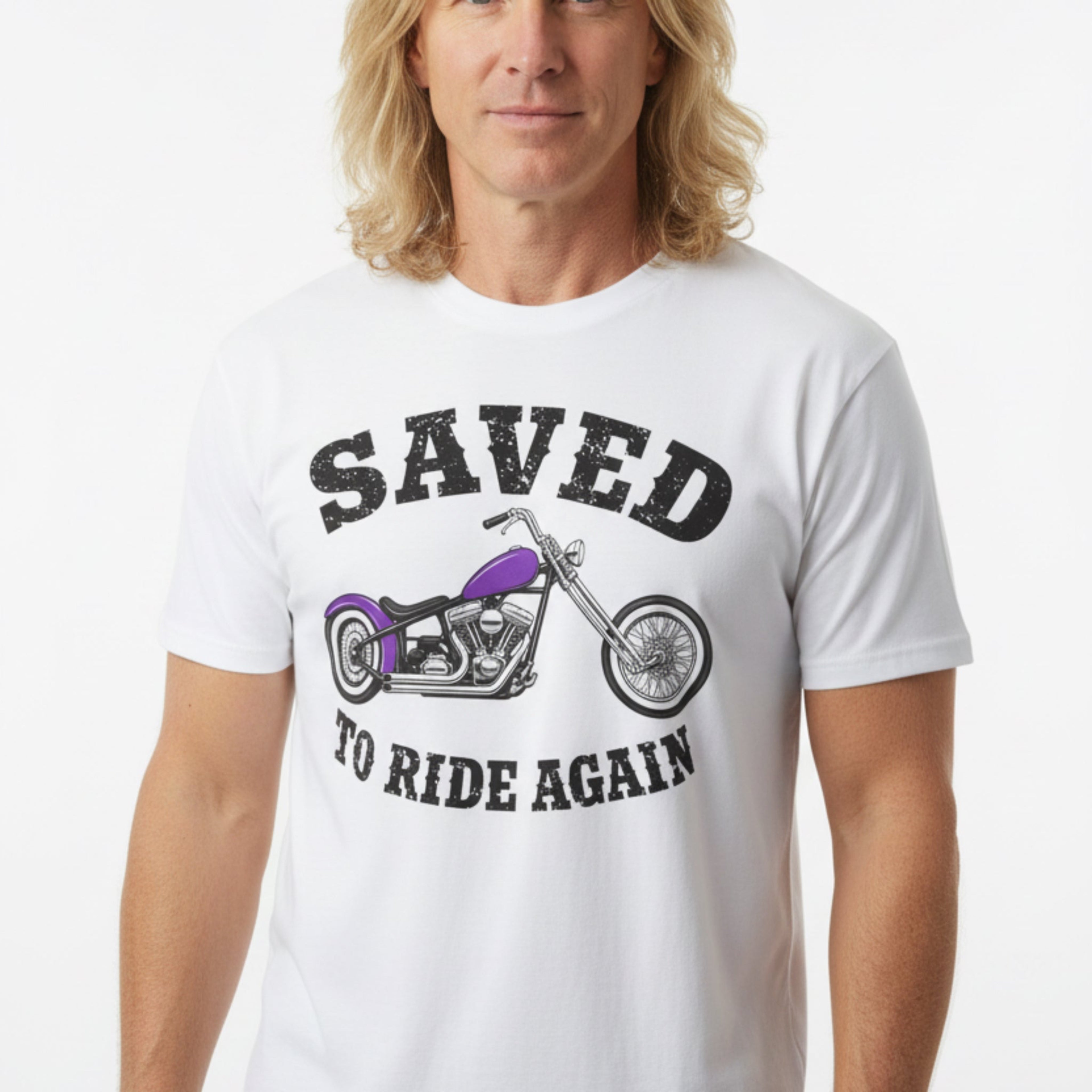 A white short-sleeve graphic T-shirt laid flat on a rustic wooden surface. The shirt features a distressed black text design reading 'SAVED TO RIDE AGAIN' surrounding an illustration of a chopper motorcycle with a purple fuel tank.