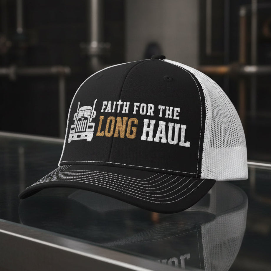 A black and white trucker hat with a graphic on the front panel showing a white semi-truck illustration and the text 'FAITH FOR THE LONG HAUL' in white and brown, set against a plain white background.