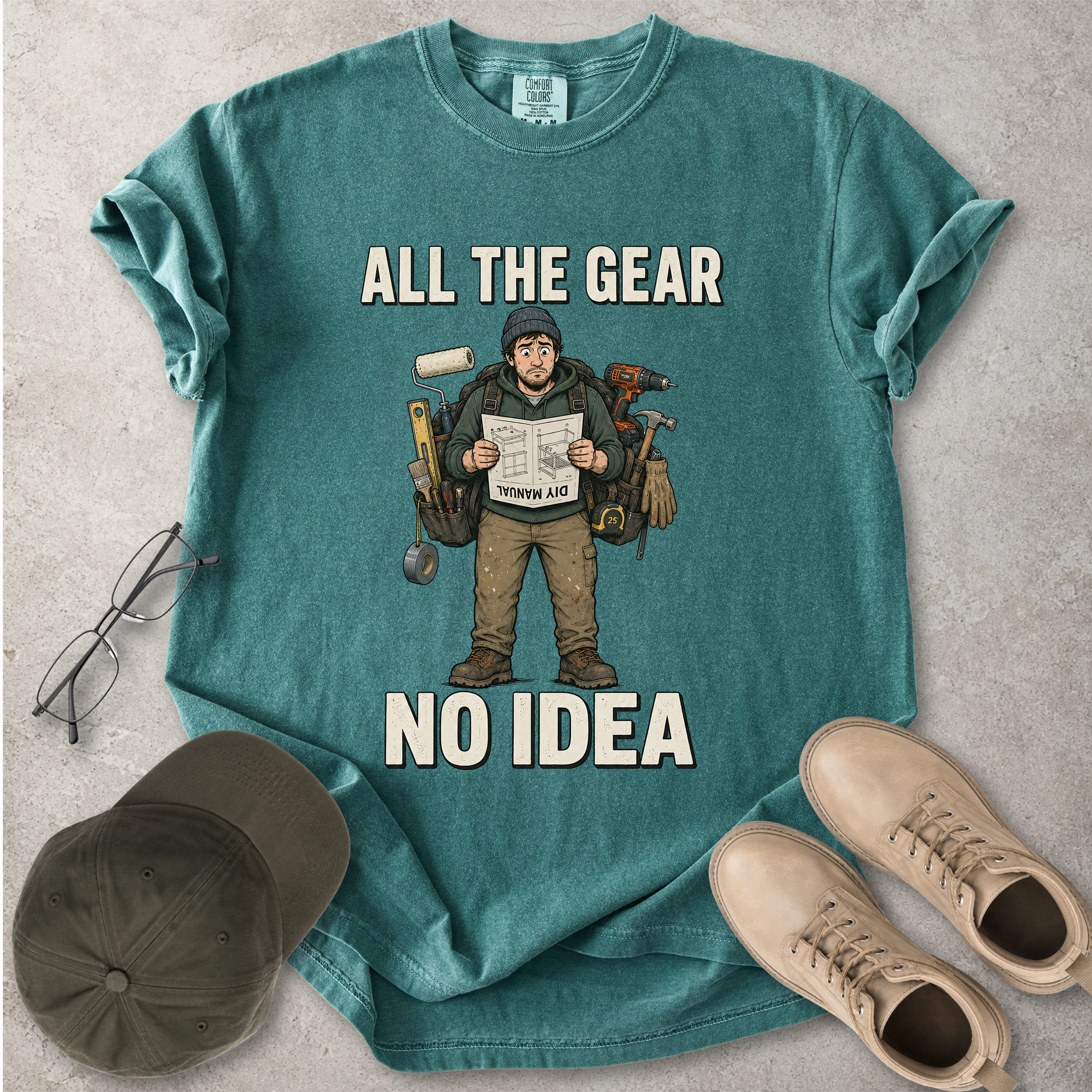 Green blue spruce Comfort Colors 1717 T-shirt with a funny All the Gear No Idea DIY graphic showing a confused handyman carrying tools and reading a manual.