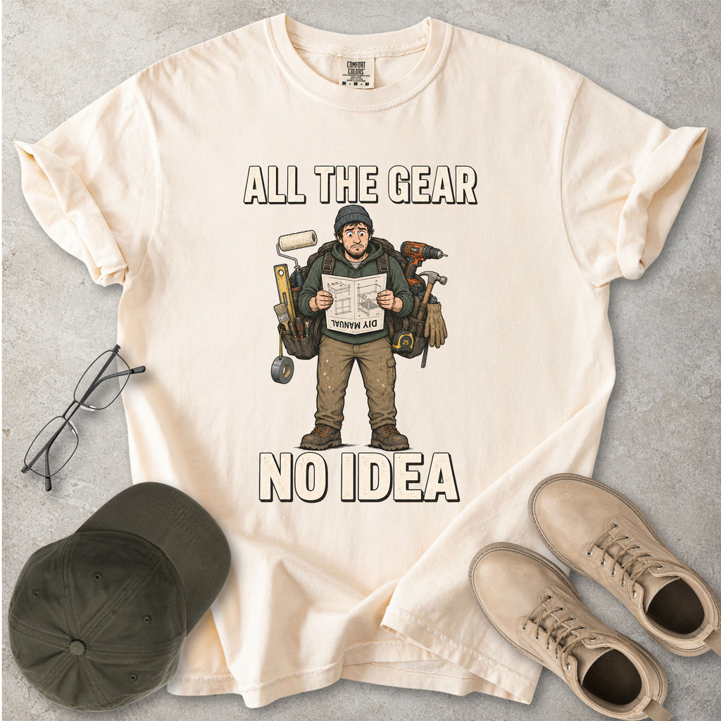 Ivory beige Comfort Colors 1717 T-shirt with a funny All the Gear No Idea DIY graphic showing a confused handyman carrying tools and reading a manual.