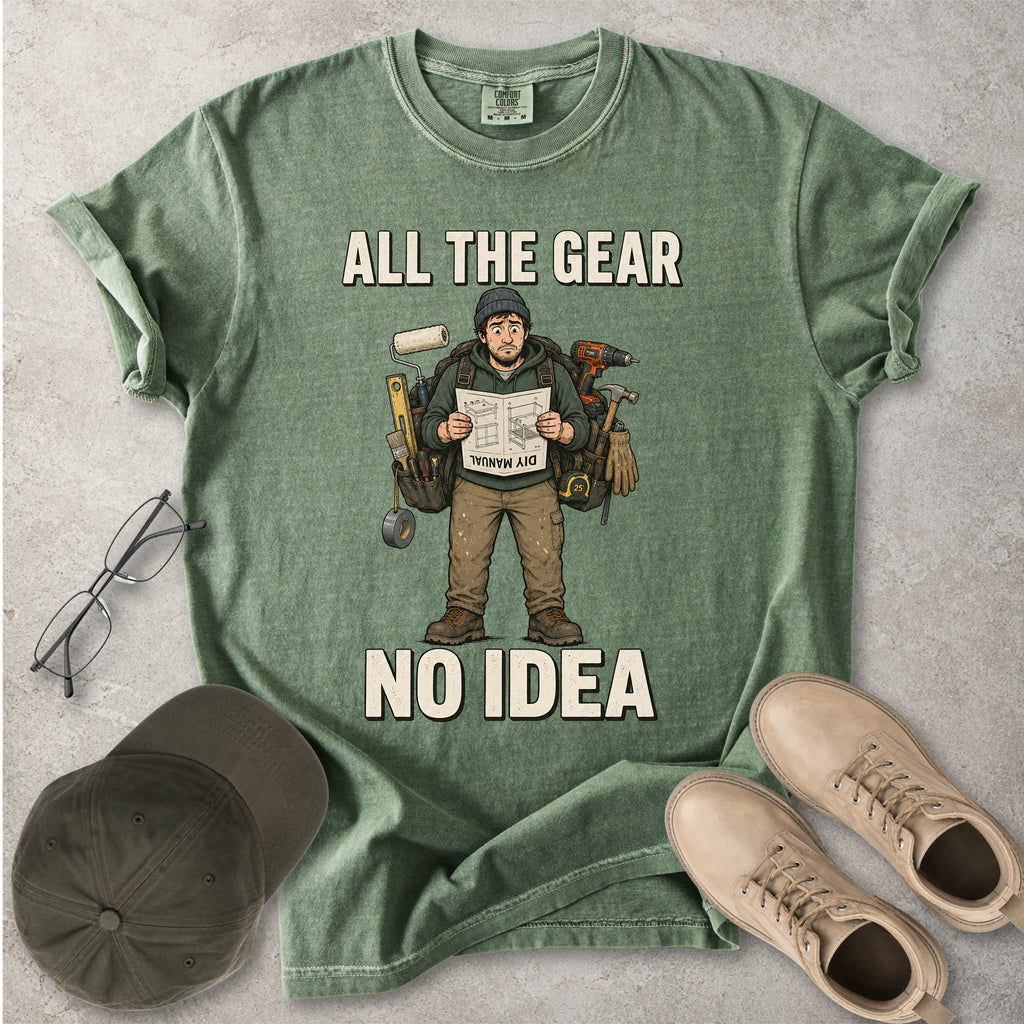 Moss green Comfort Colors 1717 T-shirt with a funny All the Gear No Idea DIY graphic showing a confused handyman carrying tools and reading a manual.