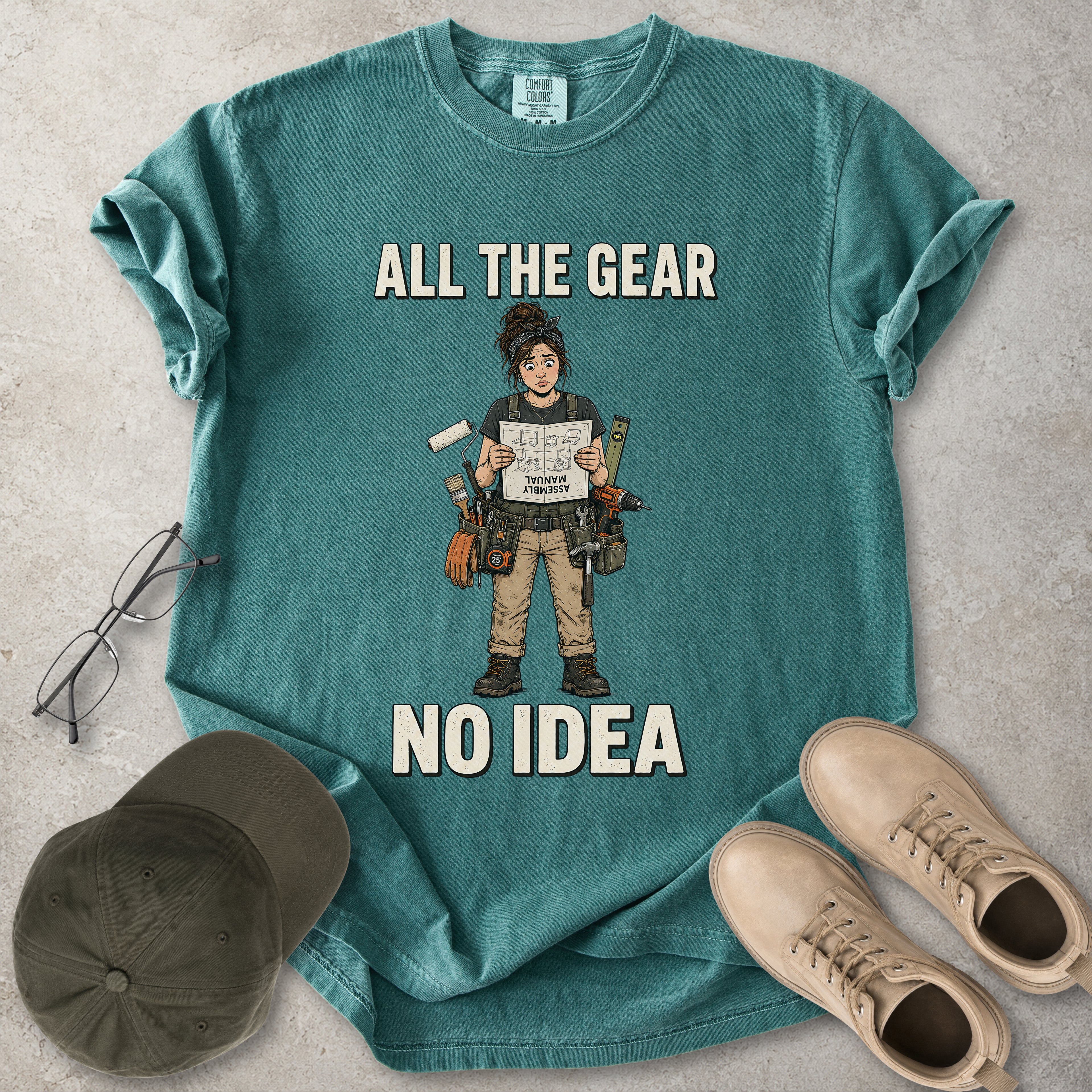 Blue spruce green Comfort Colors 1717 T-shirt with a funny All the Gear No Idea DIY graphic showing a woman with tools holding an upside-down assembly manual.