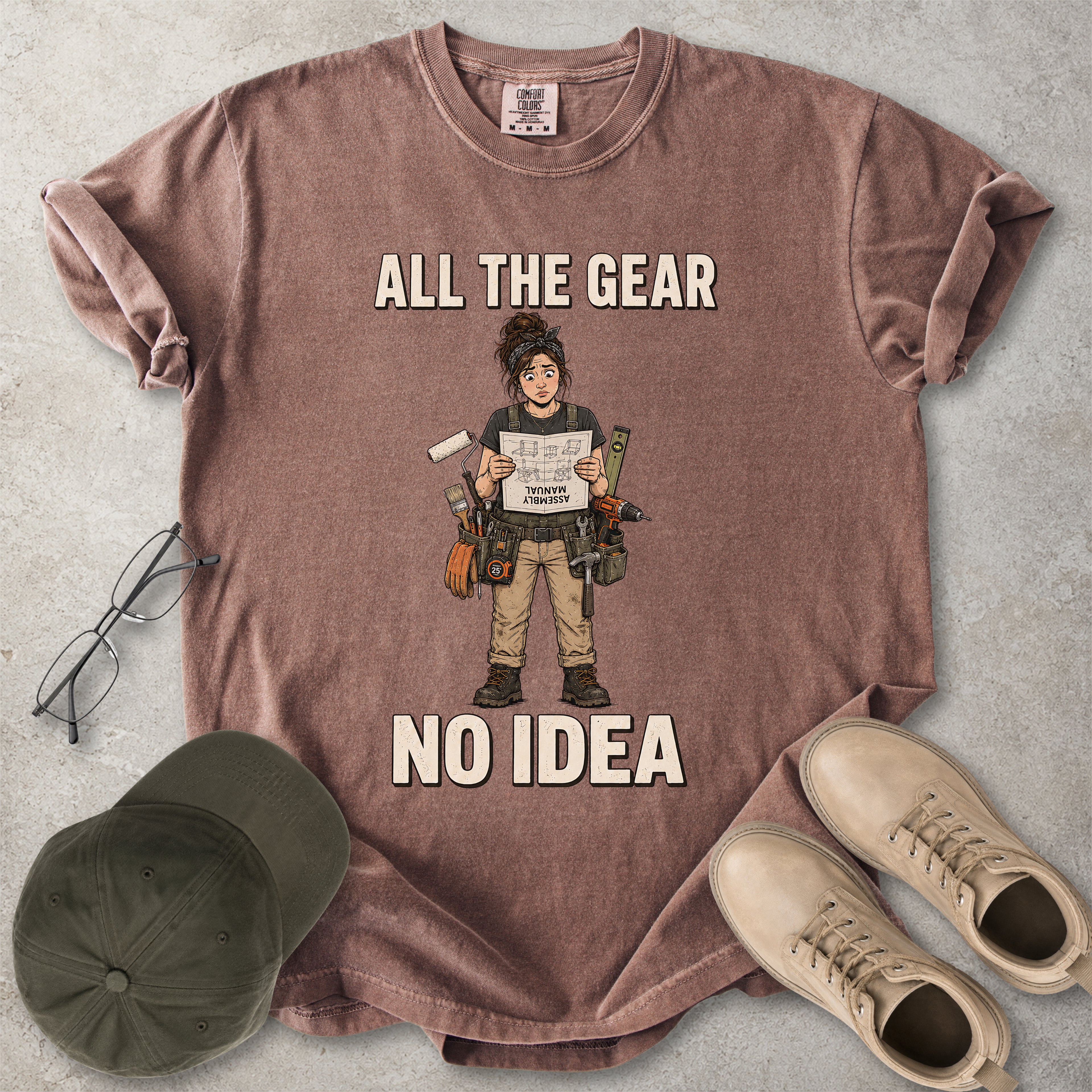 Espresso brown Comfort Colors 1717 T-shirt with a funny All the Gear No Idea DIY graphic showing a woman with tools holding an upside-down assembly manual.