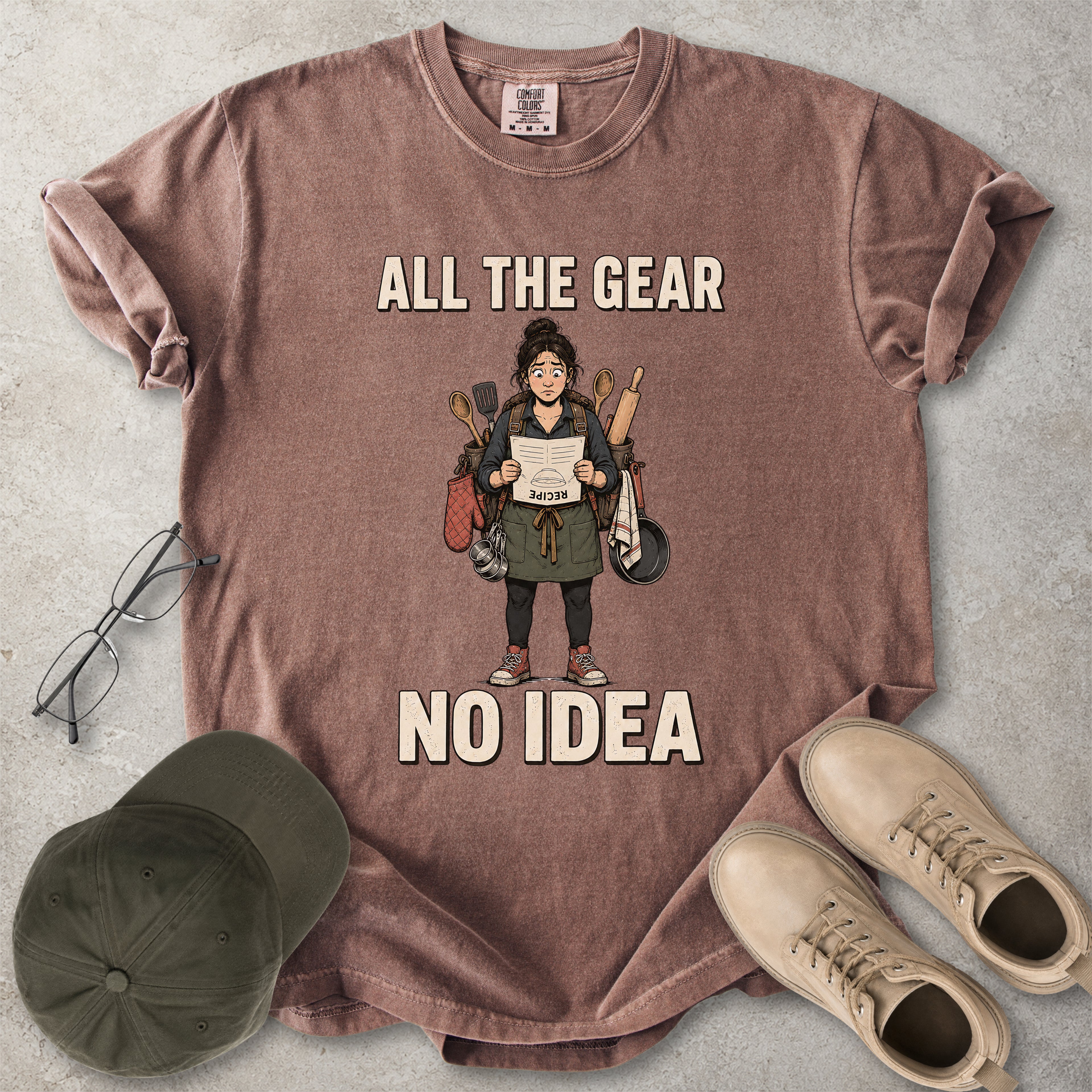 Espresso brown Comfort Colors 1717 T-shirt with a funny All the Gear No Idea cooking graphic showing a woman holding an upside-down recipe with kitchen utensils.