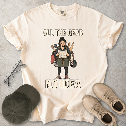 Ivory beige Comfort Colors 1717 T-shirt with a funny All the Gear No Idea cooking graphic showing a woman holding an upside-down recipe with kitchen utensils.