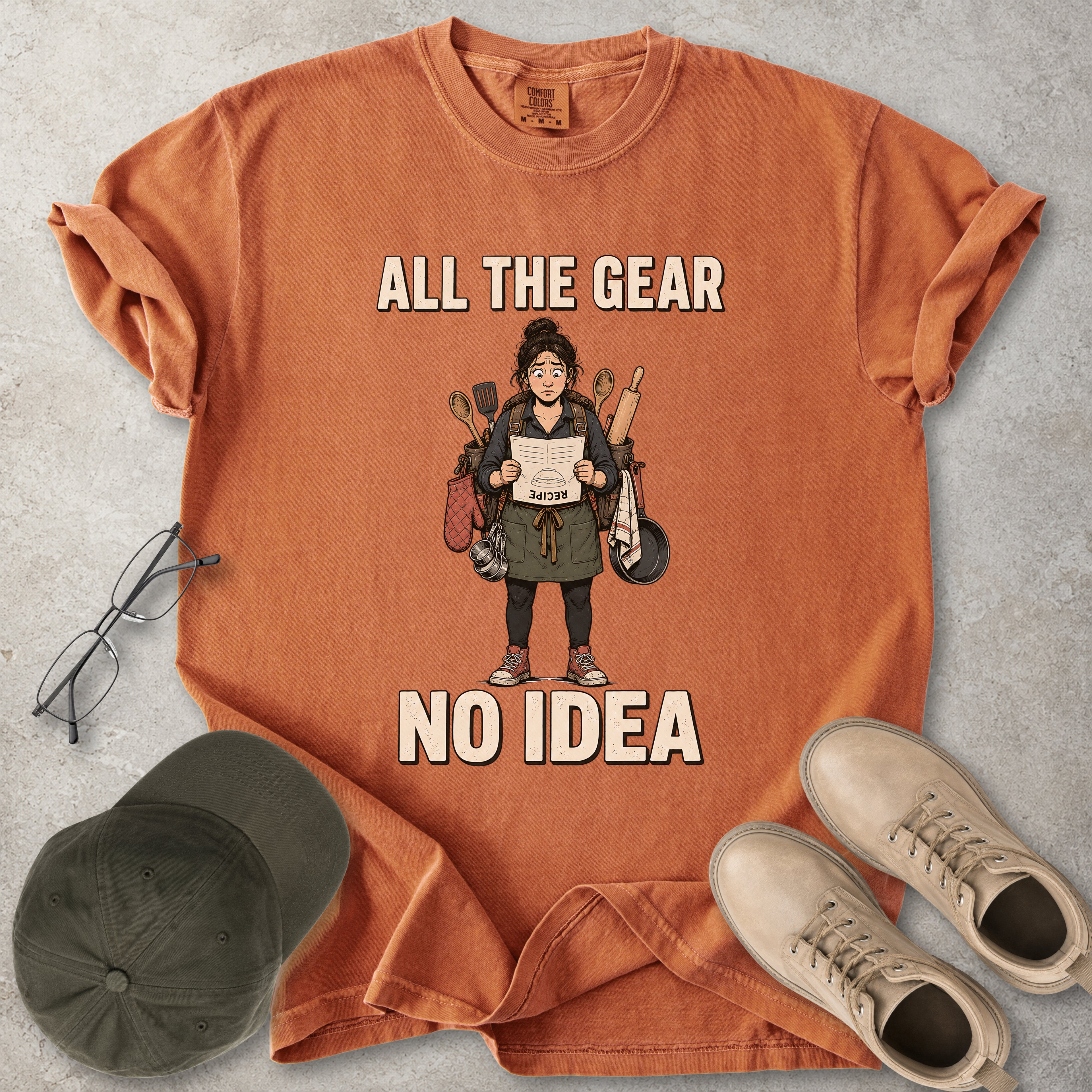 Yam orange Comfort Colors 1717 T-shirt with a funny All the Gear No Idea cooking graphic showing a woman holding an upside-down recipe with kitchen utensils.