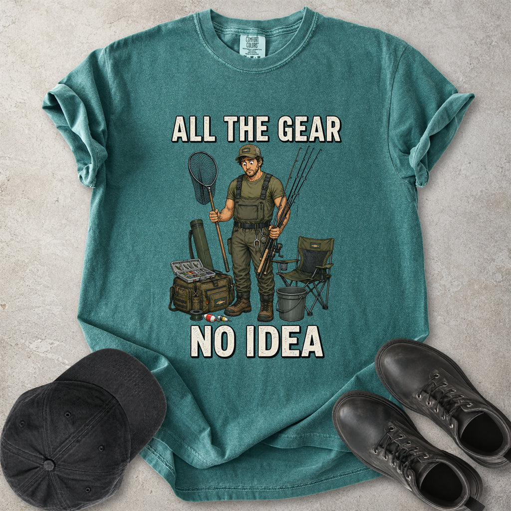 Blue spruce green Comfort Colors 1717 T-shirt with a funny All the Gear No Idea fishing graphic showing a confused fisherman holding rods and a landing net with fishing gear.