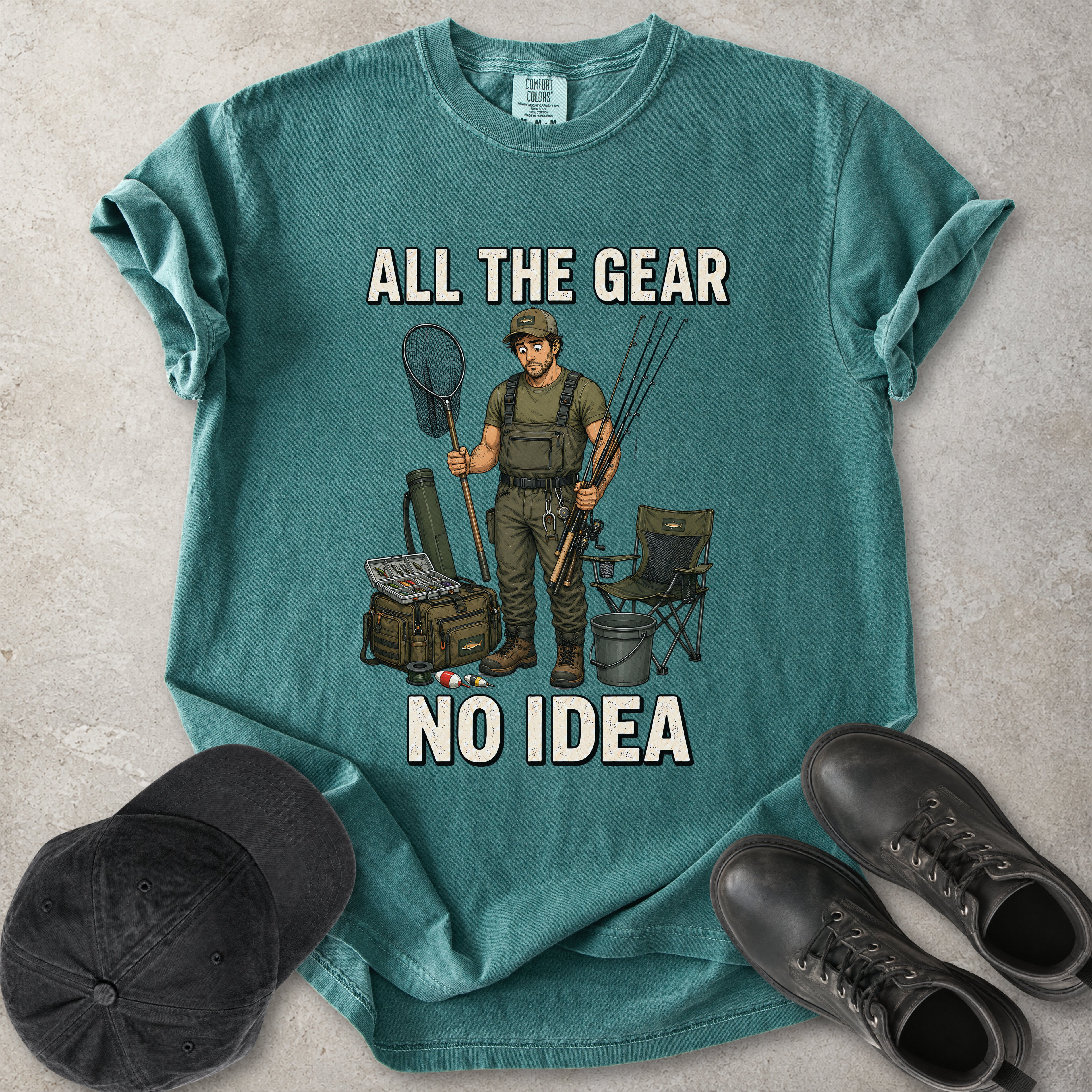 Blue spruce green Comfort Colors 1717 T-shirt with a funny All the Gear No Idea fishing graphic showing a confused fisherman holding rods and a landing net with fishing gear.