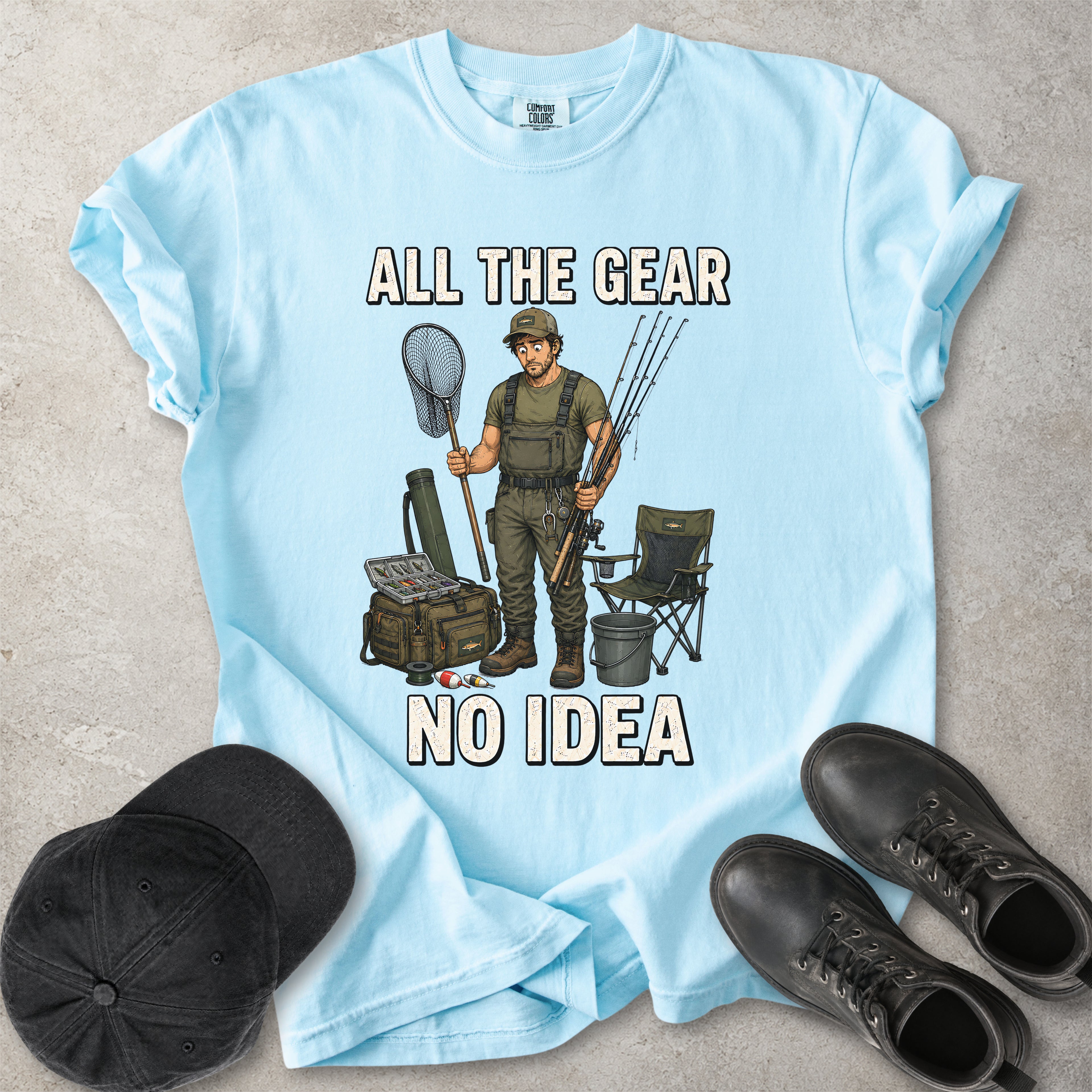 Chambray light blue Comfort Colors 1717 T-shirt with a funny All the Gear No Idea fishing graphic showing a confused fisherman holding rods and a landing net with fishing gear.