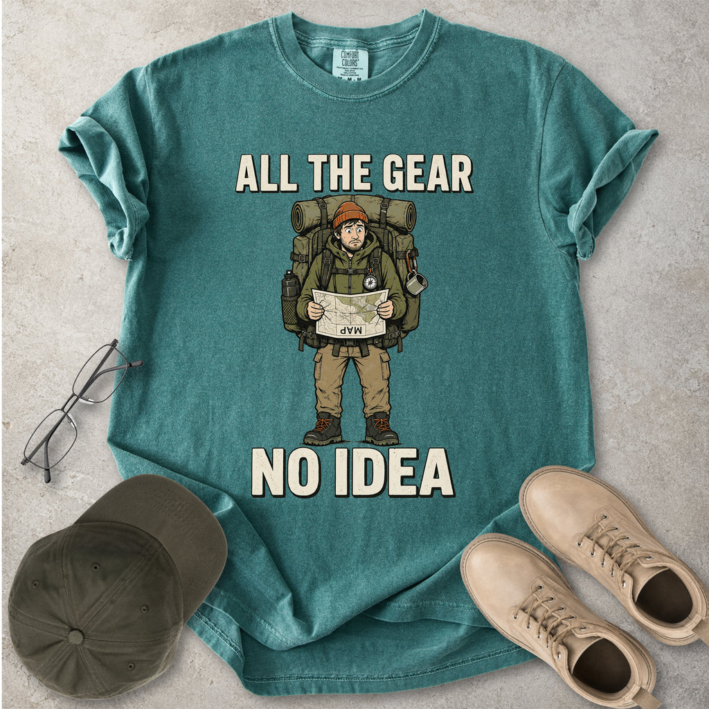 Blue spruce Comfort Colors 1717 T-shirt with a funny All the Gear No Idea hiking graphic showing a confused hiker holding an upside-down map with a large backpack.