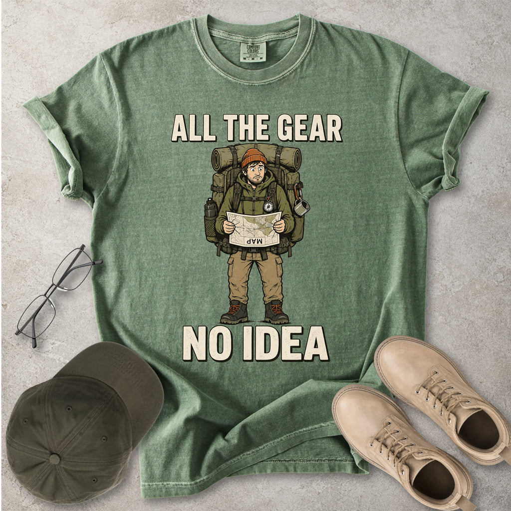 Moss green Comfort Colors 1717 T-shirt with a funny All the Gear No Idea hiking graphic showing a confused hiker holding an upside-down map with a large backpack.