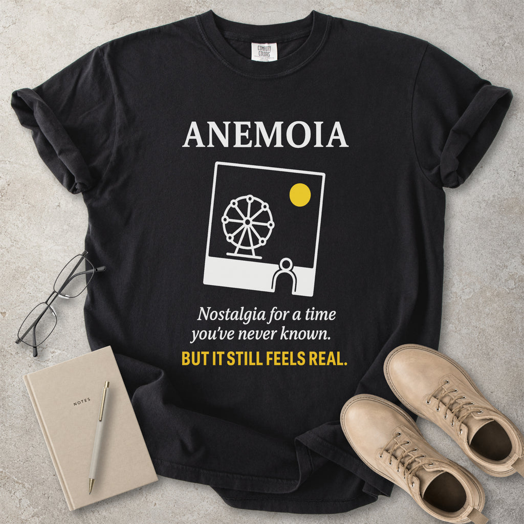 Black t-shirt with 'Anemoia' design and text on a concrete surface with accessories.