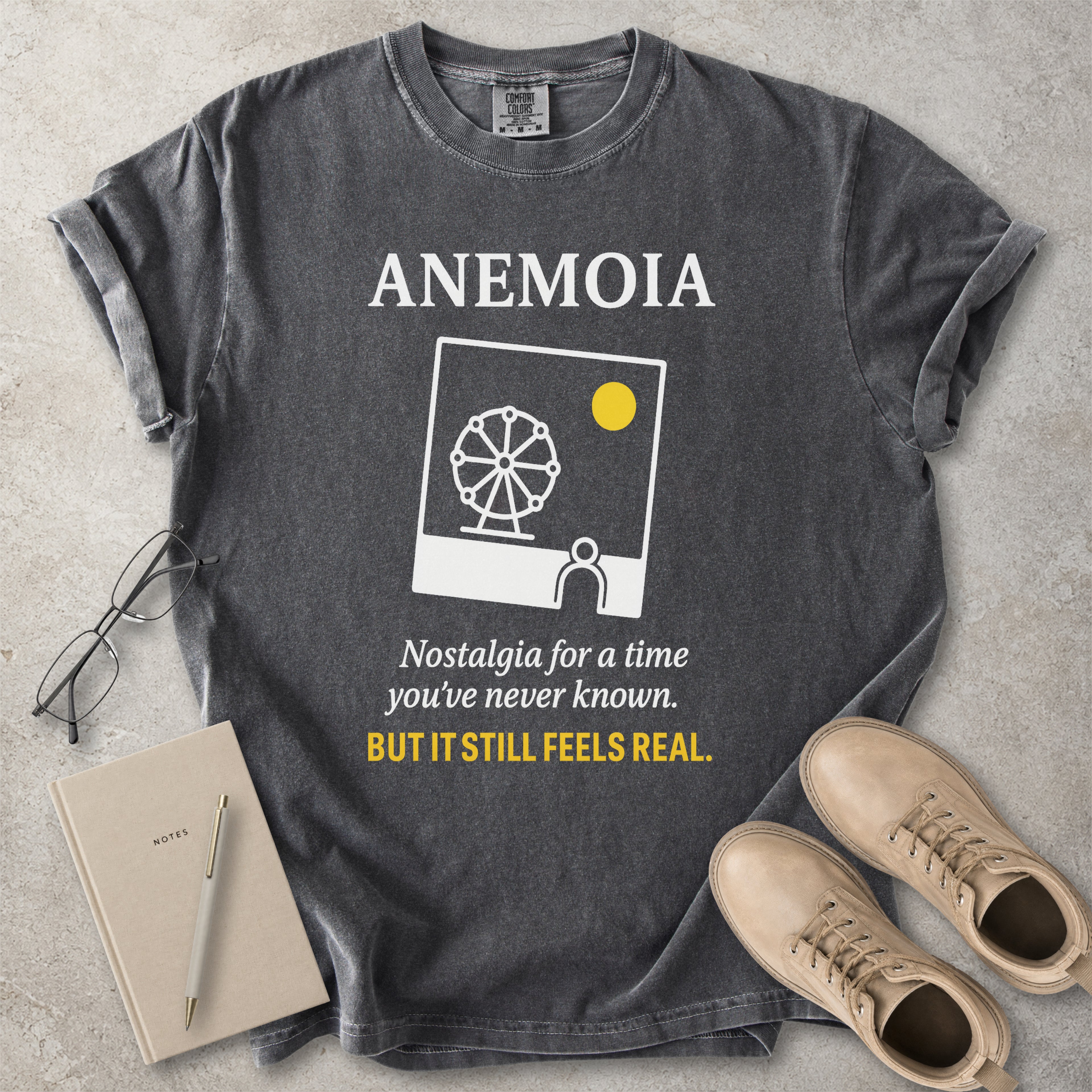 Pepper grey Comfort Colors graphic T-shirt with Anemoia text, photo-style ferris wheel design and yellow accent text, styled with notebook, glasses and tan boots