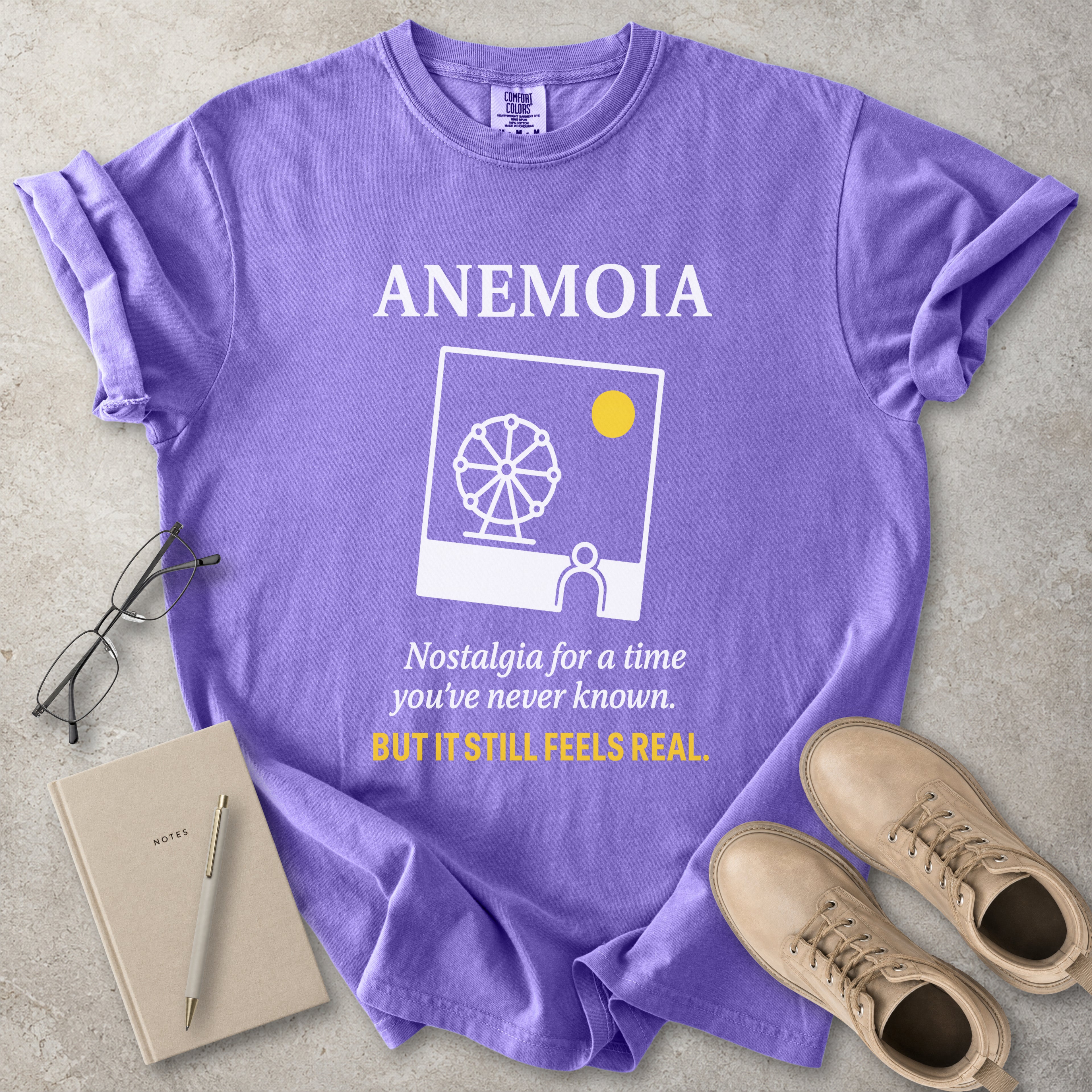 Violet purple Comfort Colors graphic T-shirt with Anemoia text, photo-style ferris wheel design and yellow accent text, styled with notebook, glasses and tan boots