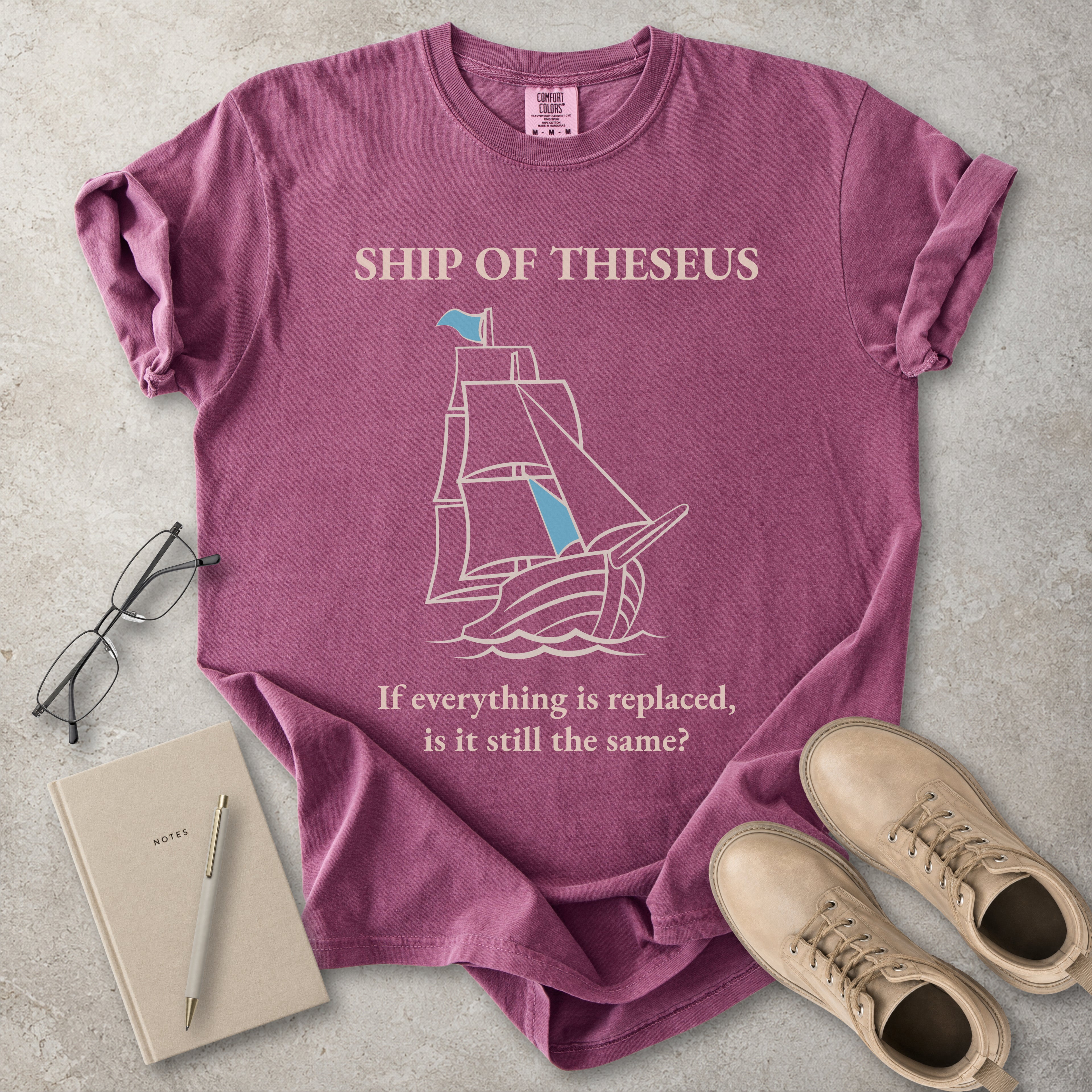 Berry red Comfort Colors graphic T-shirt with Ship of Theseus text, line-art sailing ship and the phrase if everything is replaced is it still the same