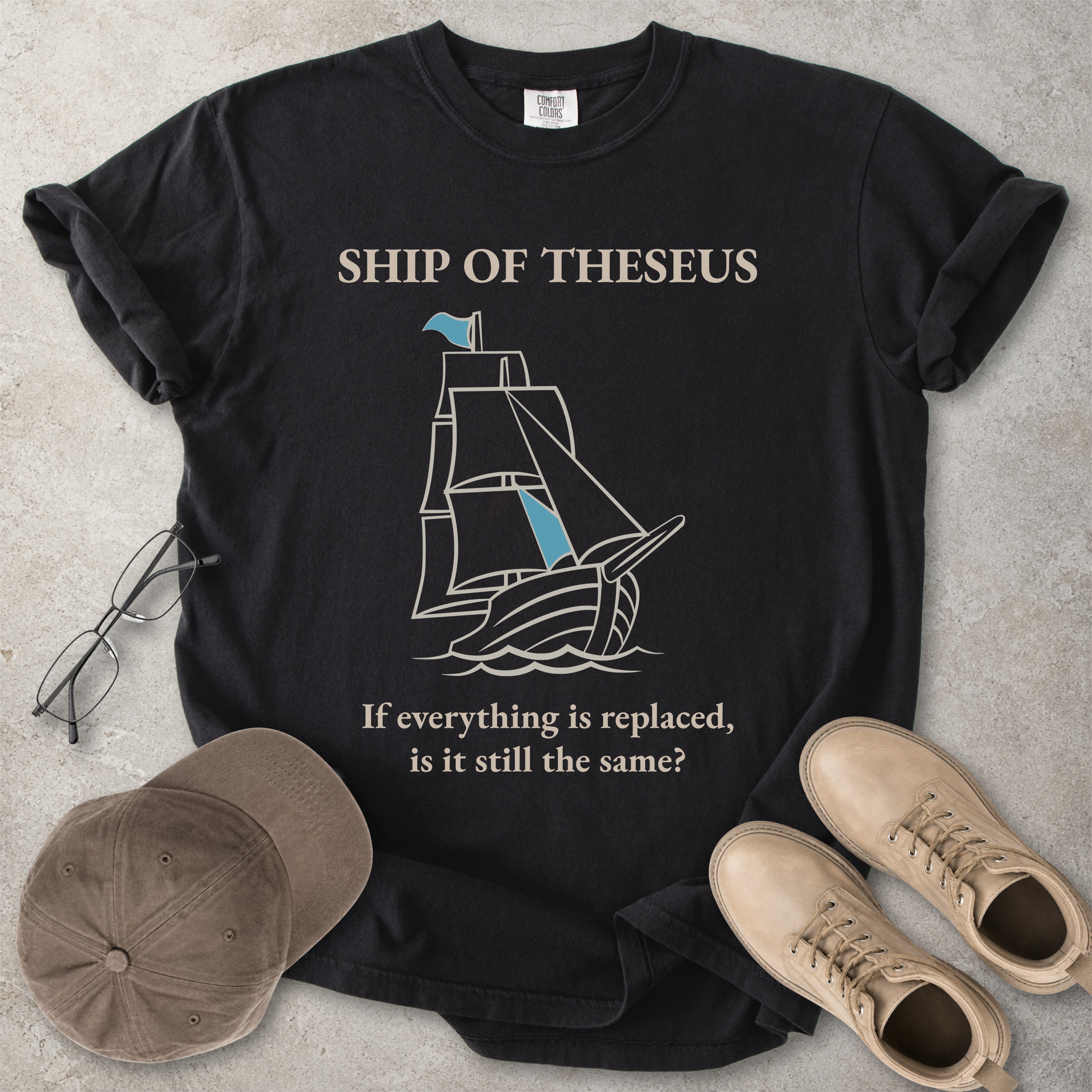 Black Comfort Colors graphic T-shirt with Ship of Theseus text, line-art sailing ship and the phrase if everything is replaced is it still the same