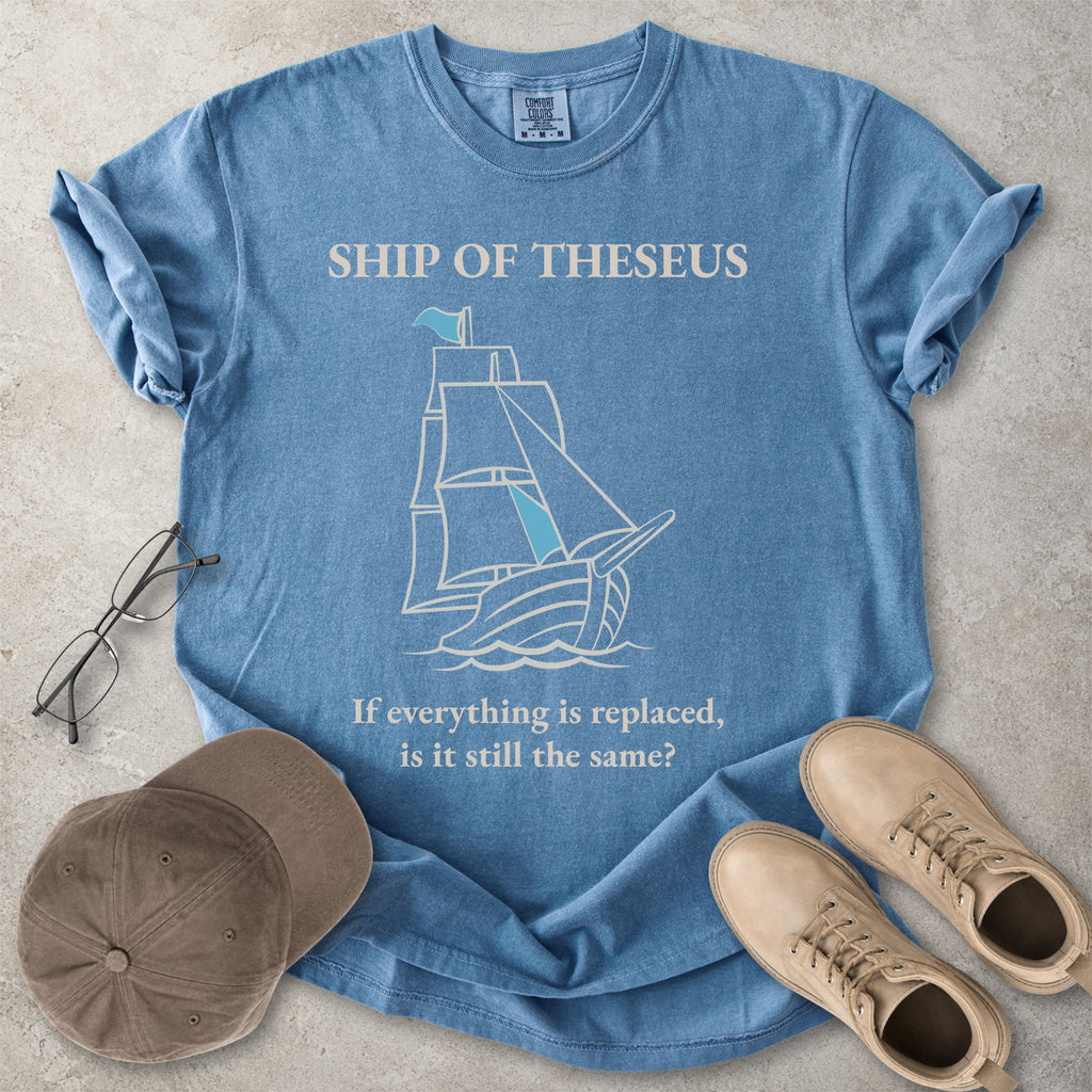Blue jean Comfort Colors graphic T-shirt with Ship of Theseus text, line-art sailing ship and the phrase if everything is replaced is it still the same