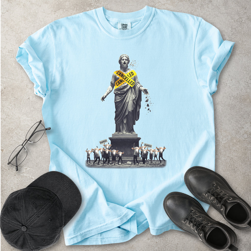 Light blue Comfort Colors graphic T-shirt with cancelled statue and crowd design, styled with black cap, glasses and black boots