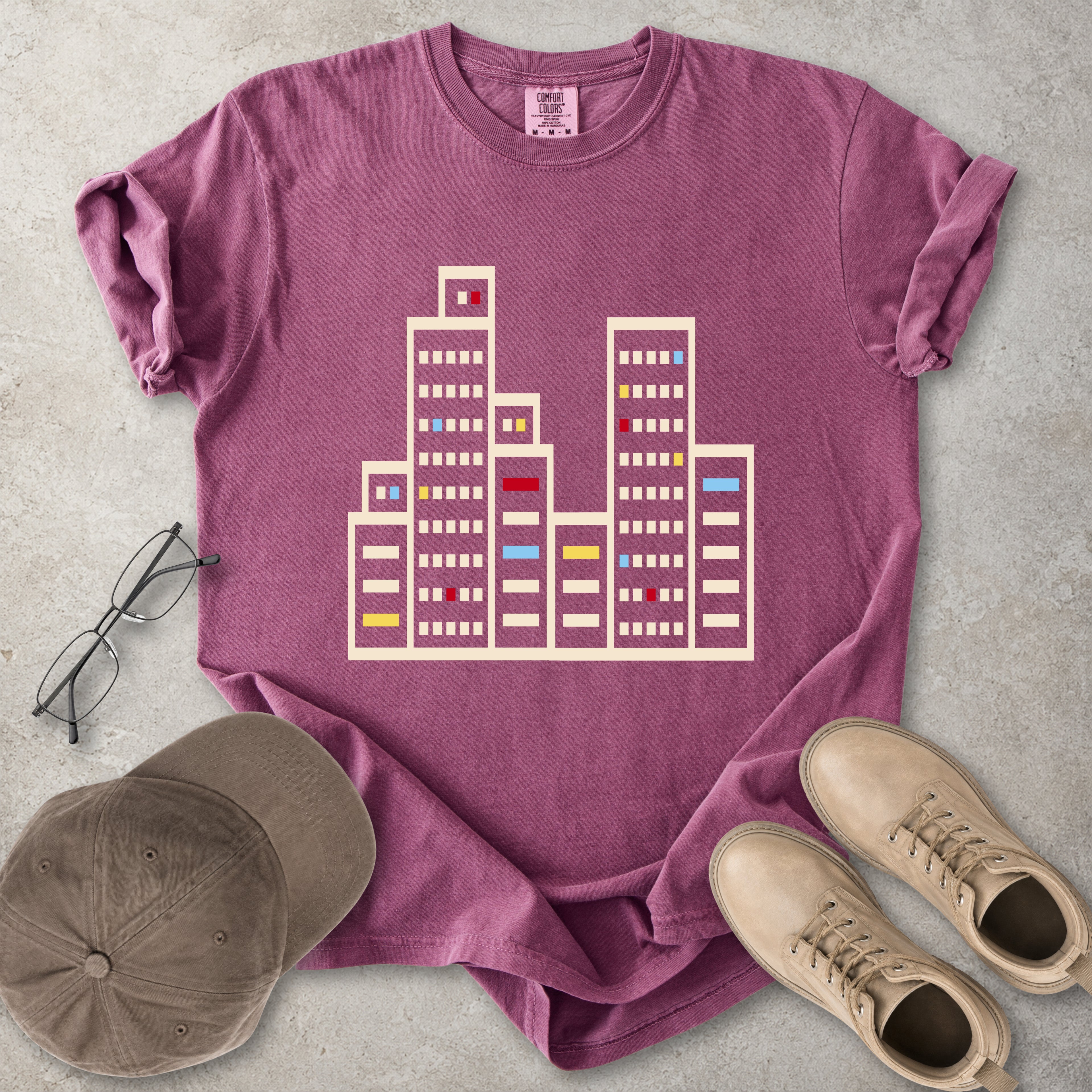 Berry red Comfort Colors graphic T-shirt with a minimalist cityscape window design, styled with glasses, cap and tan boots