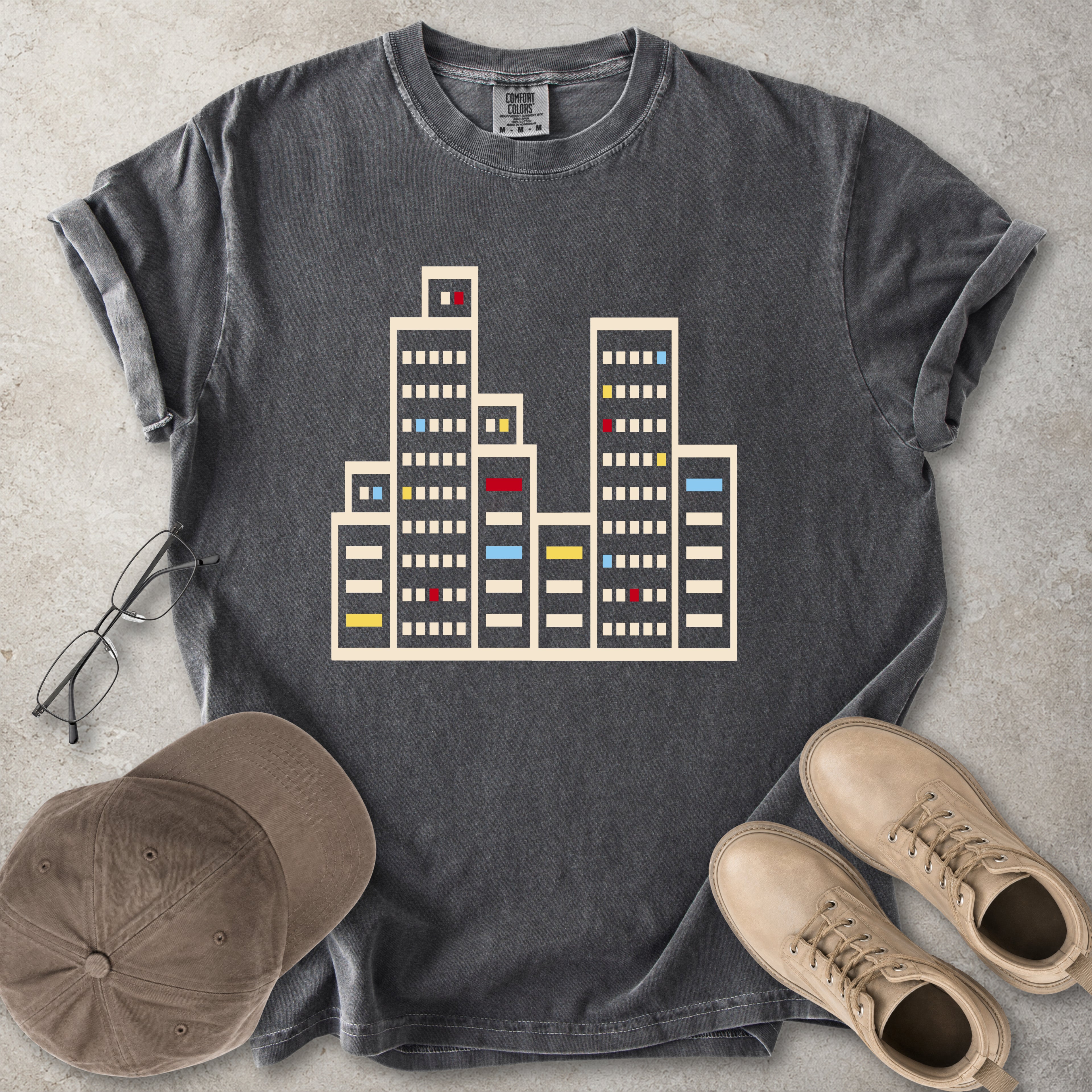 Pepper grey Comfort Colors graphic T-shirt with a minimalist cityscape window design, styled with glasses, cap and tan boots