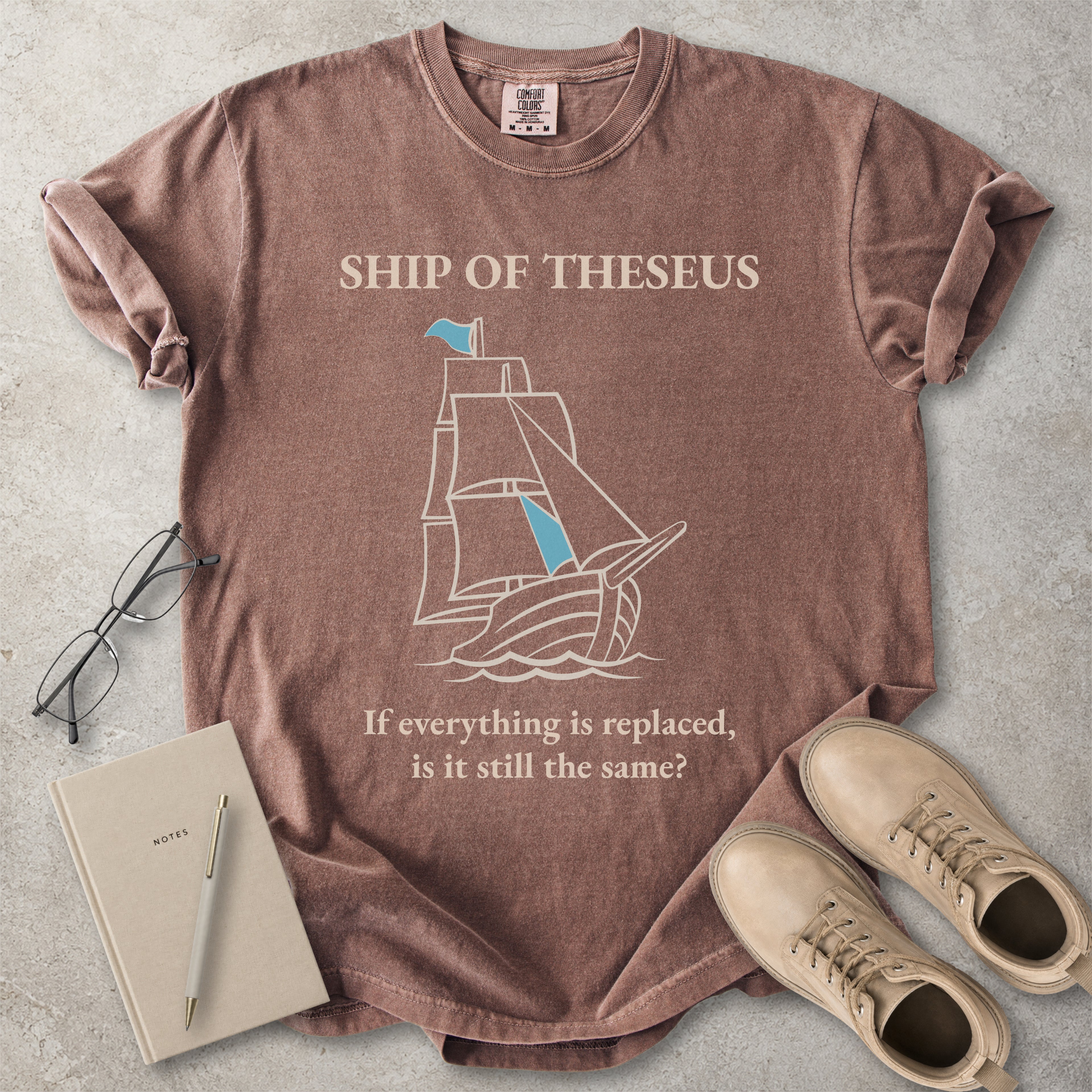 Espresso brown Comfort Colors graphic T-shirt with Ship of Theseus text, line-art sailing ship and the phrase if everything is replaced is it still the same
