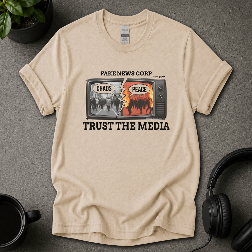 Beige t-shirt with graphic design and text on a gray surface with a plant and mug in the background