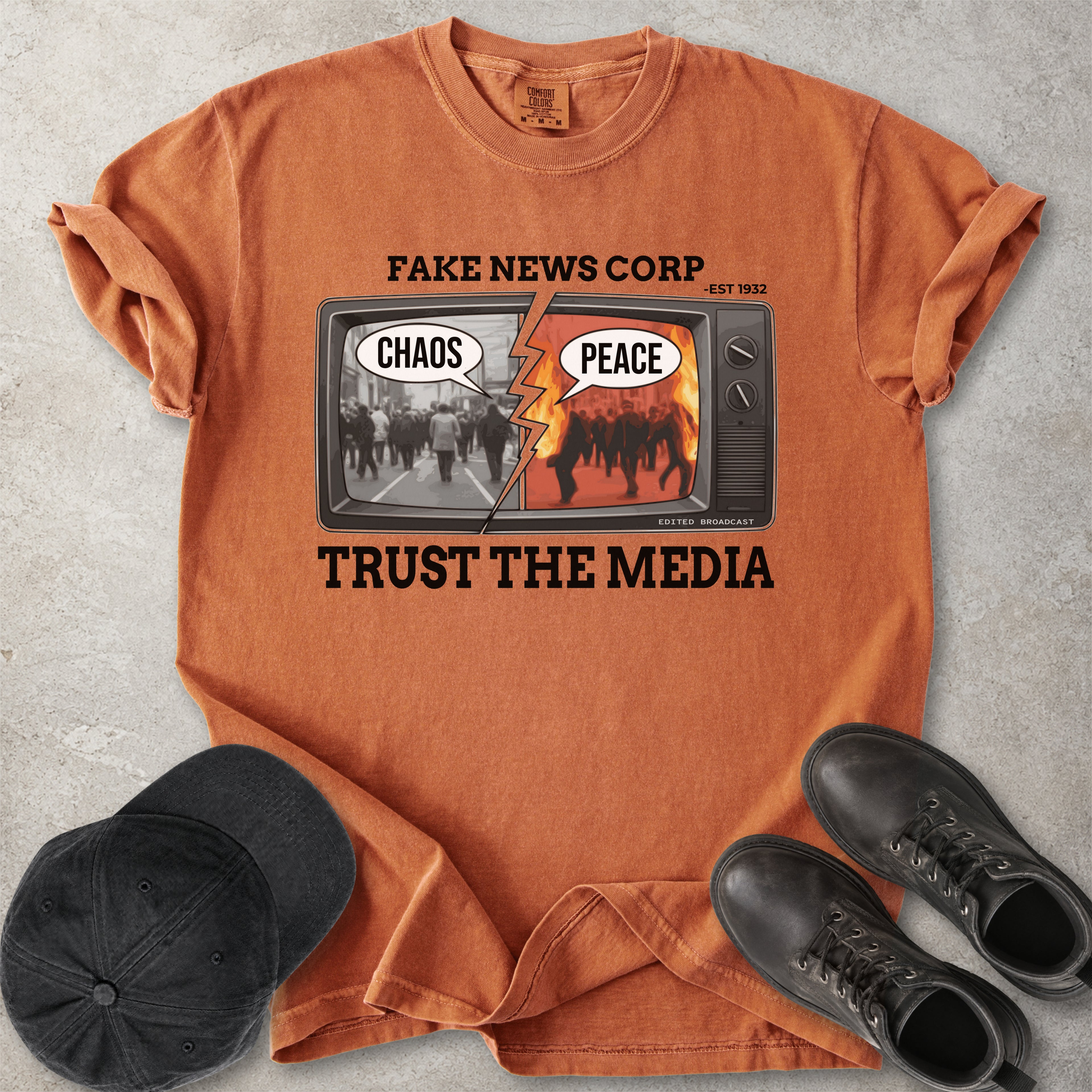 Yam orange Comfort Colors graphic T-shirt with Fake News Corp trust the media TV design showing chaos and peace screens, styled with black cap and boots
