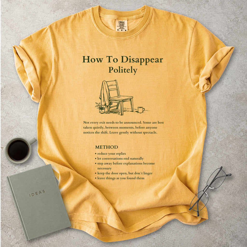 Mustard yellow Comfort Colors graphic T-shirt with green How To Disappear Politely design, chair illustration and quiet exit method text, styled with coffee, notebook and glasses