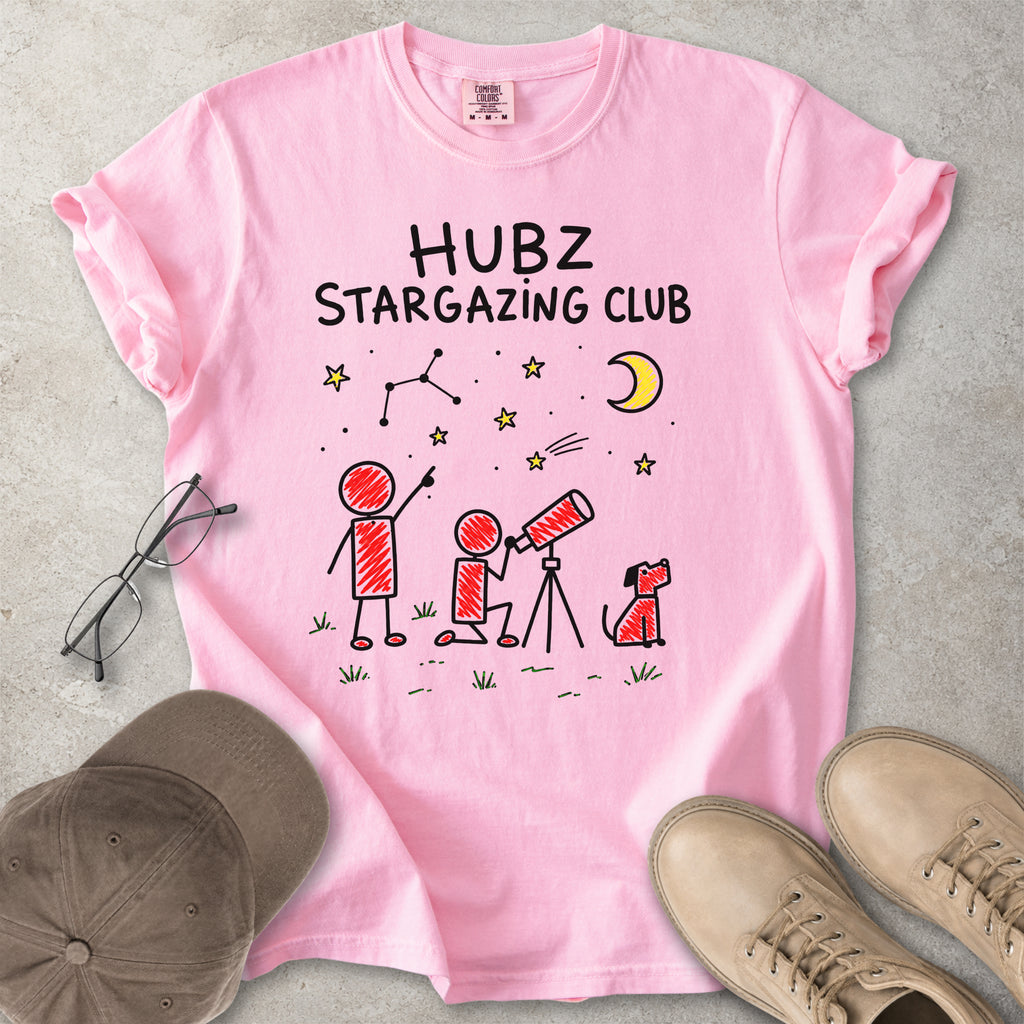 Pink t-shirt with 'HUBZ Stargazing Club' design on a gray surface with accessories.