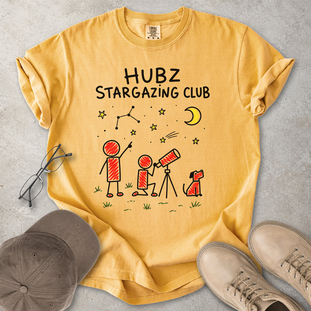 Yellow t-shirt with 'HUBZ Stargazing Club' design on a gray surface with accessories.