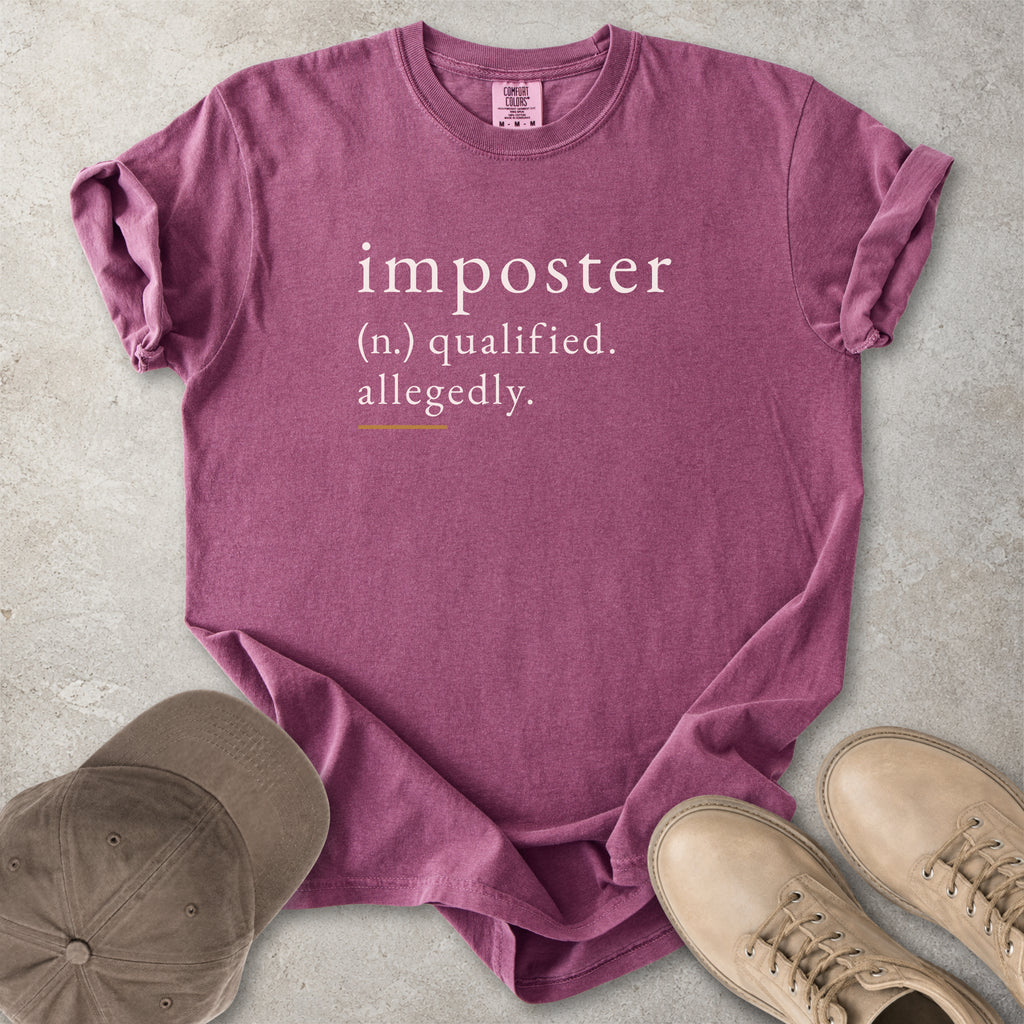 Berry red Comfort Colors graphic T-shirt with imposter definition text reading qualified allegedly, styled with brown cap and tan boots
