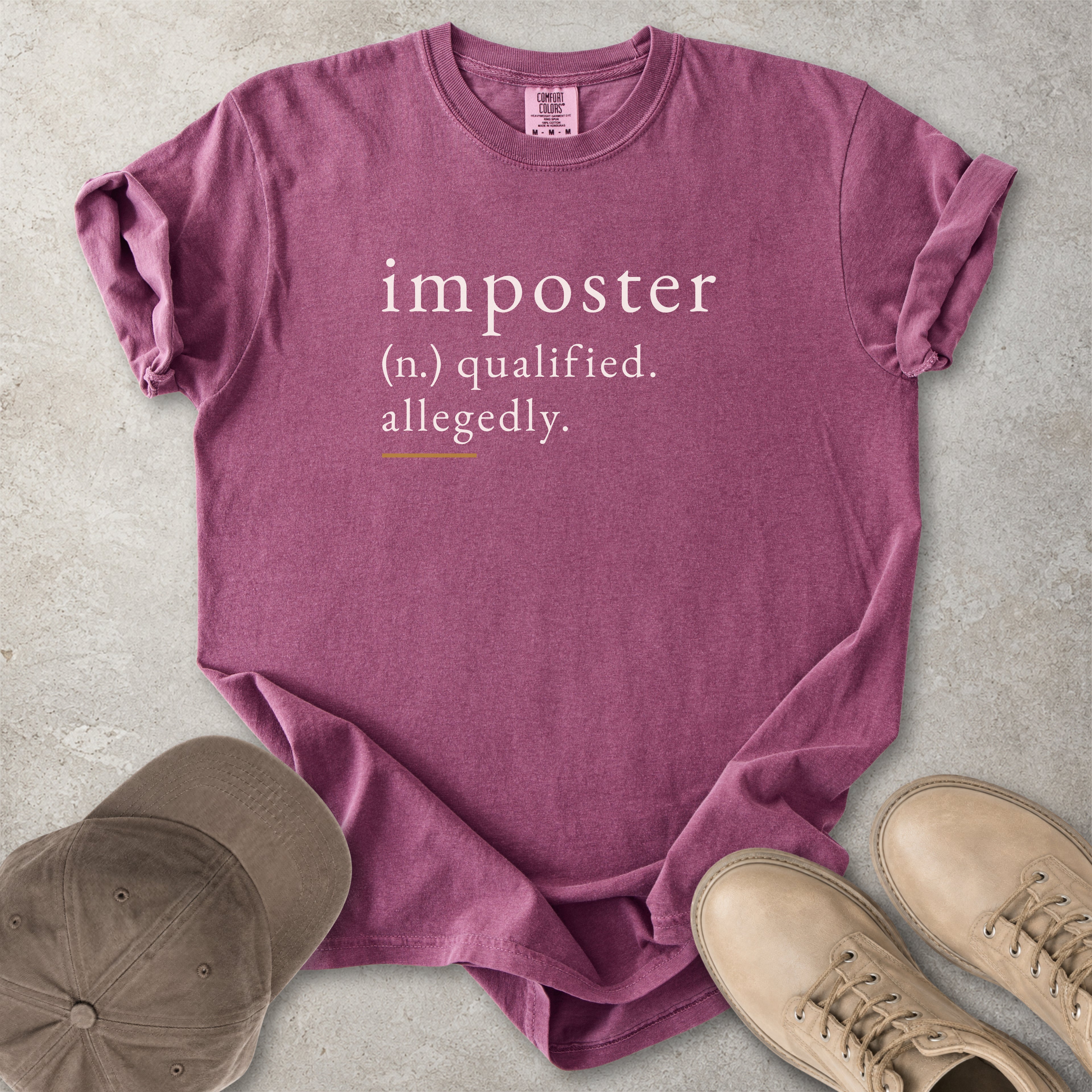 Berry red Comfort Colors graphic T-shirt with imposter definition text reading qualified allegedly, styled with brown cap and tan boots