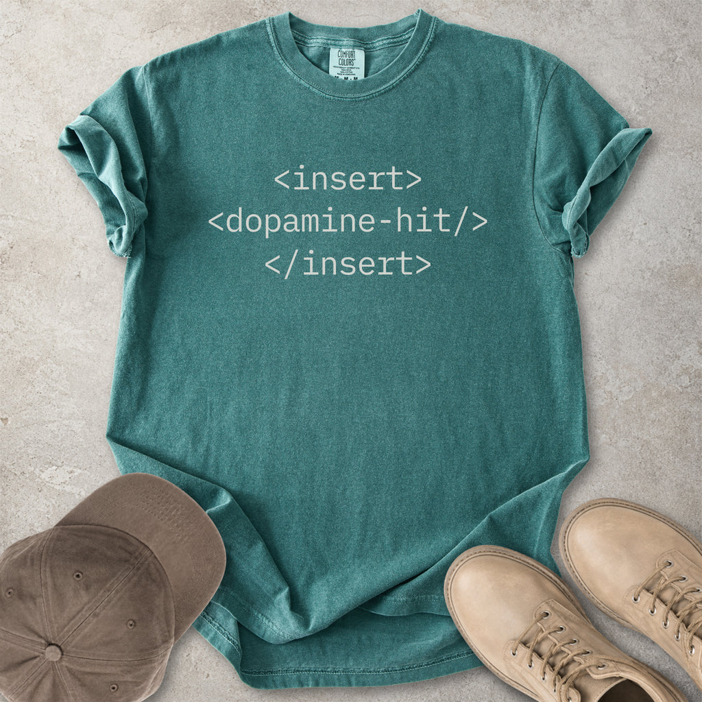Teal t-shirt with computer code text, cap, and shoes on a concrete surface