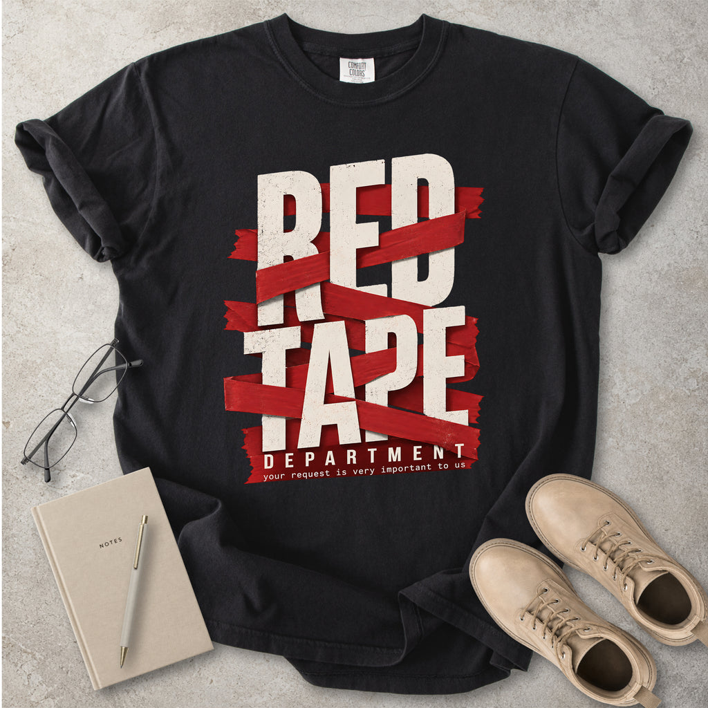 Black t-shirt with 'Red Tape Department' graphic on a gray surface with notebook and boots.