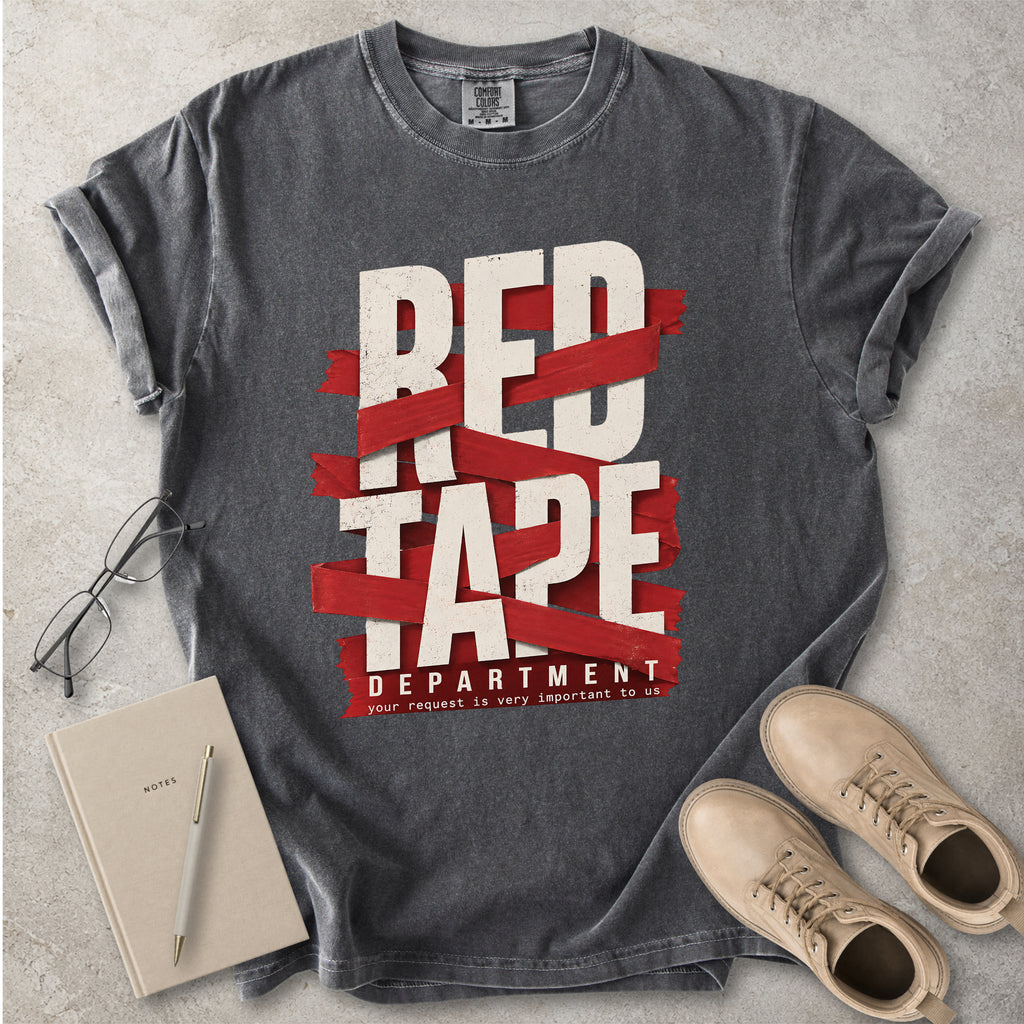 Gray t-shirt with 'Red Tape Department' design on a concrete surface with notebook, pen, and boots.