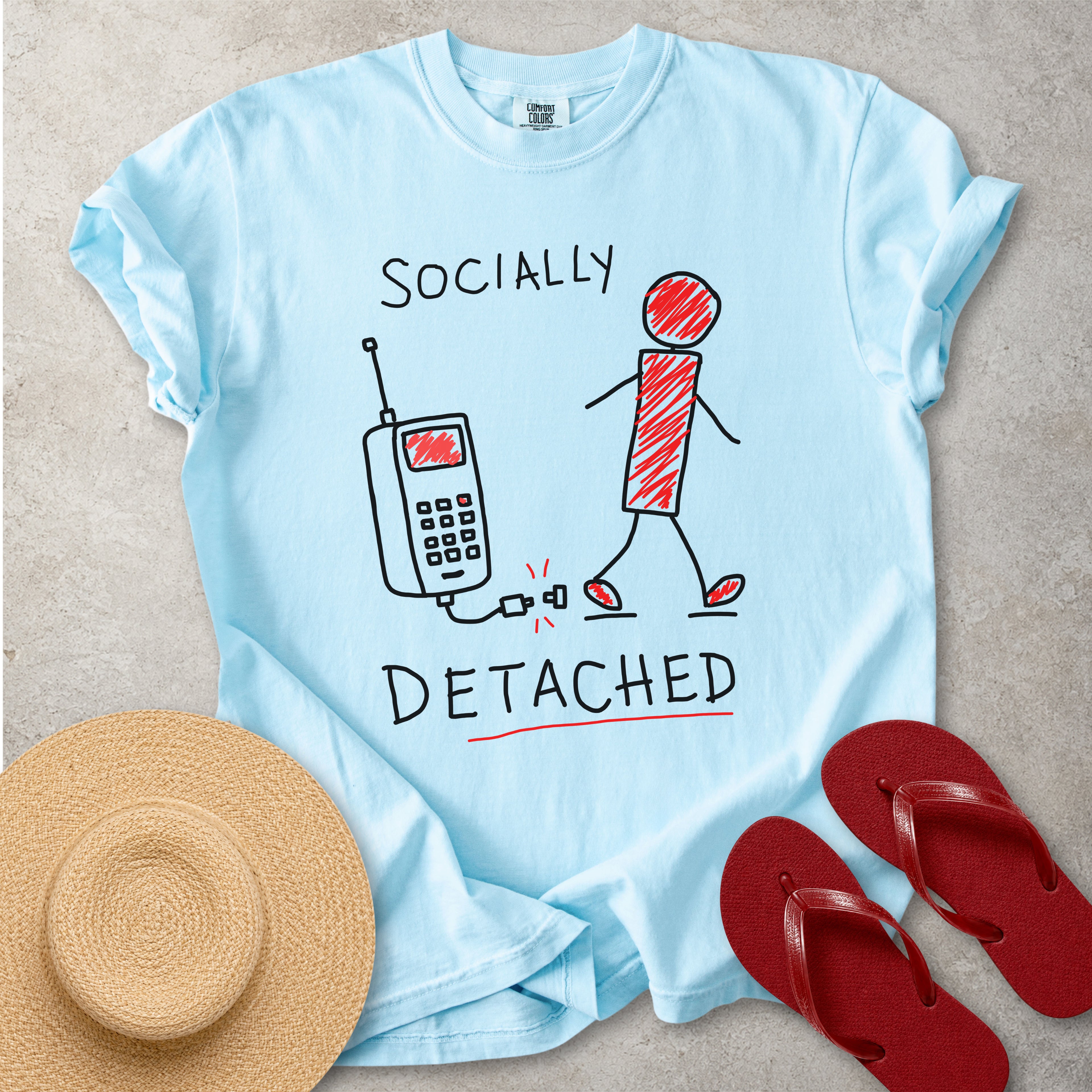Light blue Comfort Colors graphic T-shirt with hand-drawn socially detached design showing a person walking away from an unplugged phone, styled with straw hat and red flip flops