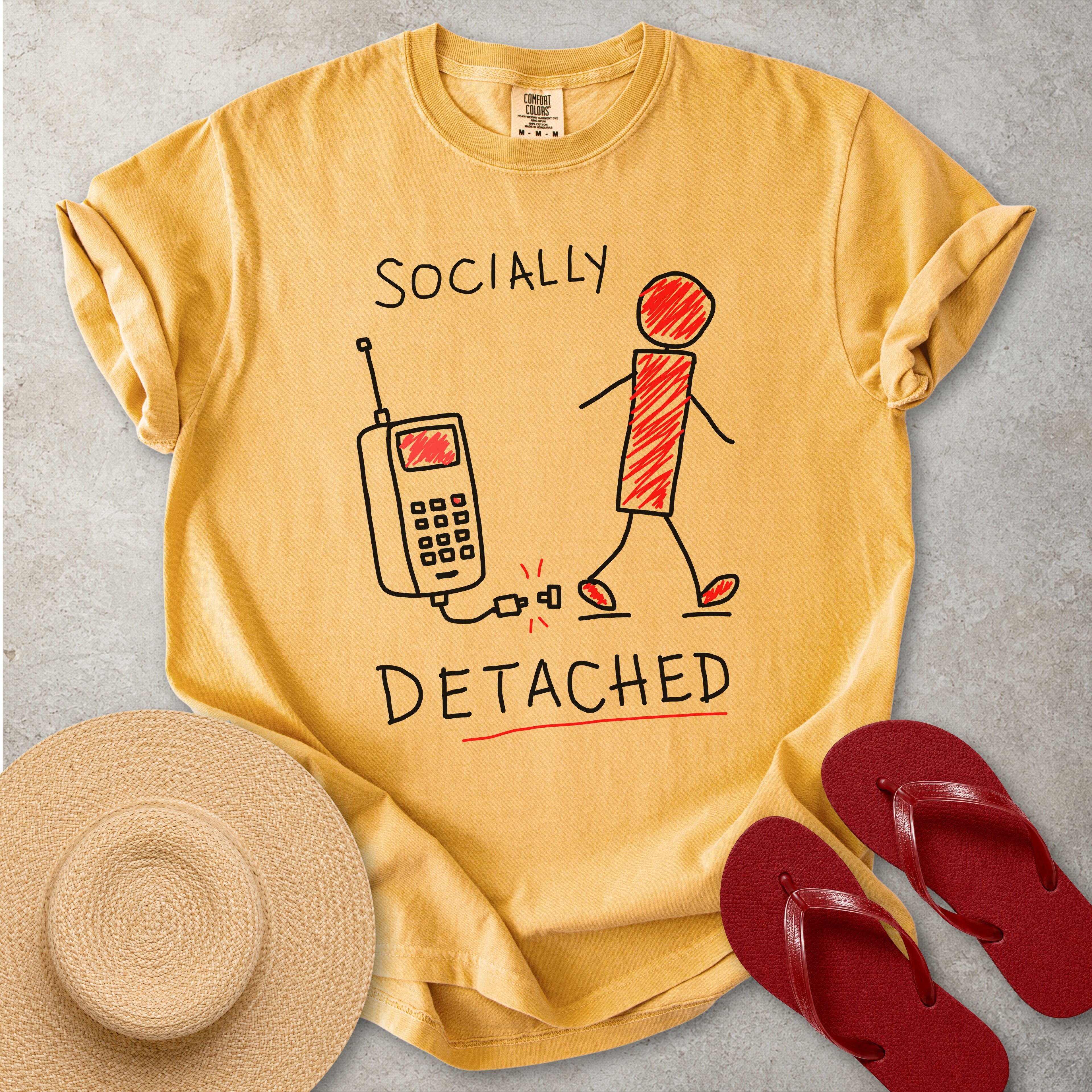 Yellow Comfort Colors graphic T-shirt with hand-drawn socially detached design showing a person walking away from an unplugged phone, styled with straw hat and red flip flops