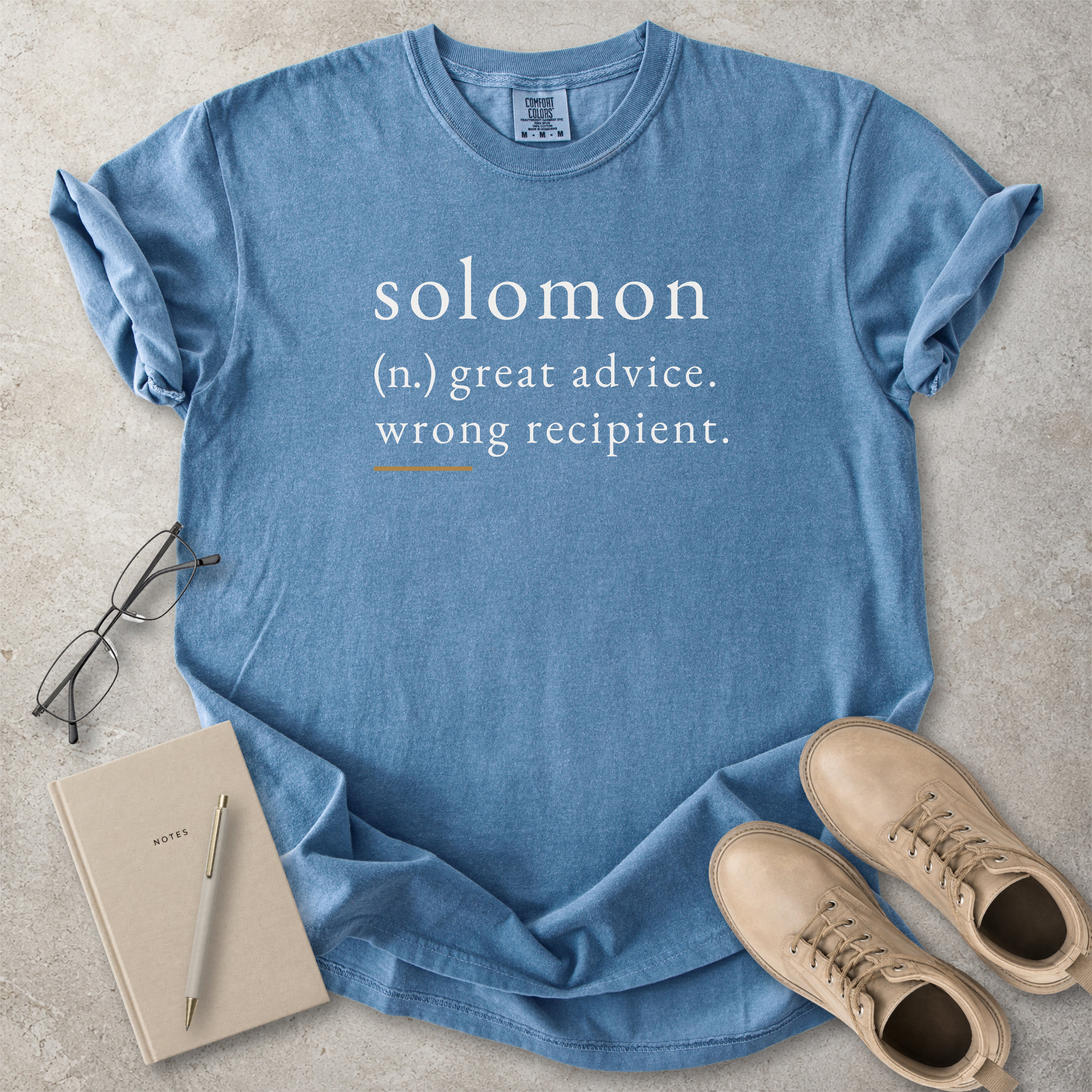 Blue Comfort Colors graphic T-shirt with Solomon definition text reading great advice wrong recipient, styled with notebook, pen and tan boots