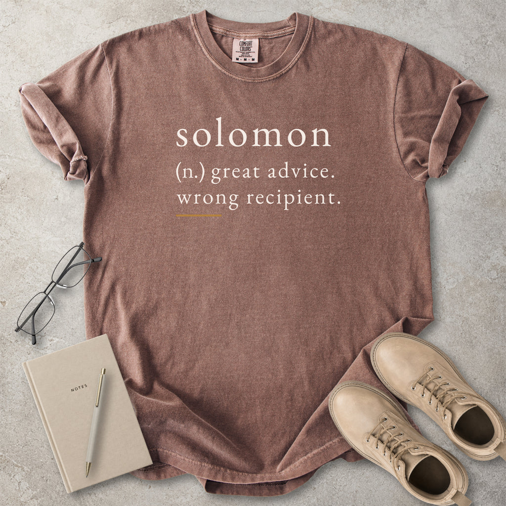 Brown Comfort Colors graphic T-shirt with Solomon definition text reading great advice wrong recipient, styled with notebook, pen and tan boots