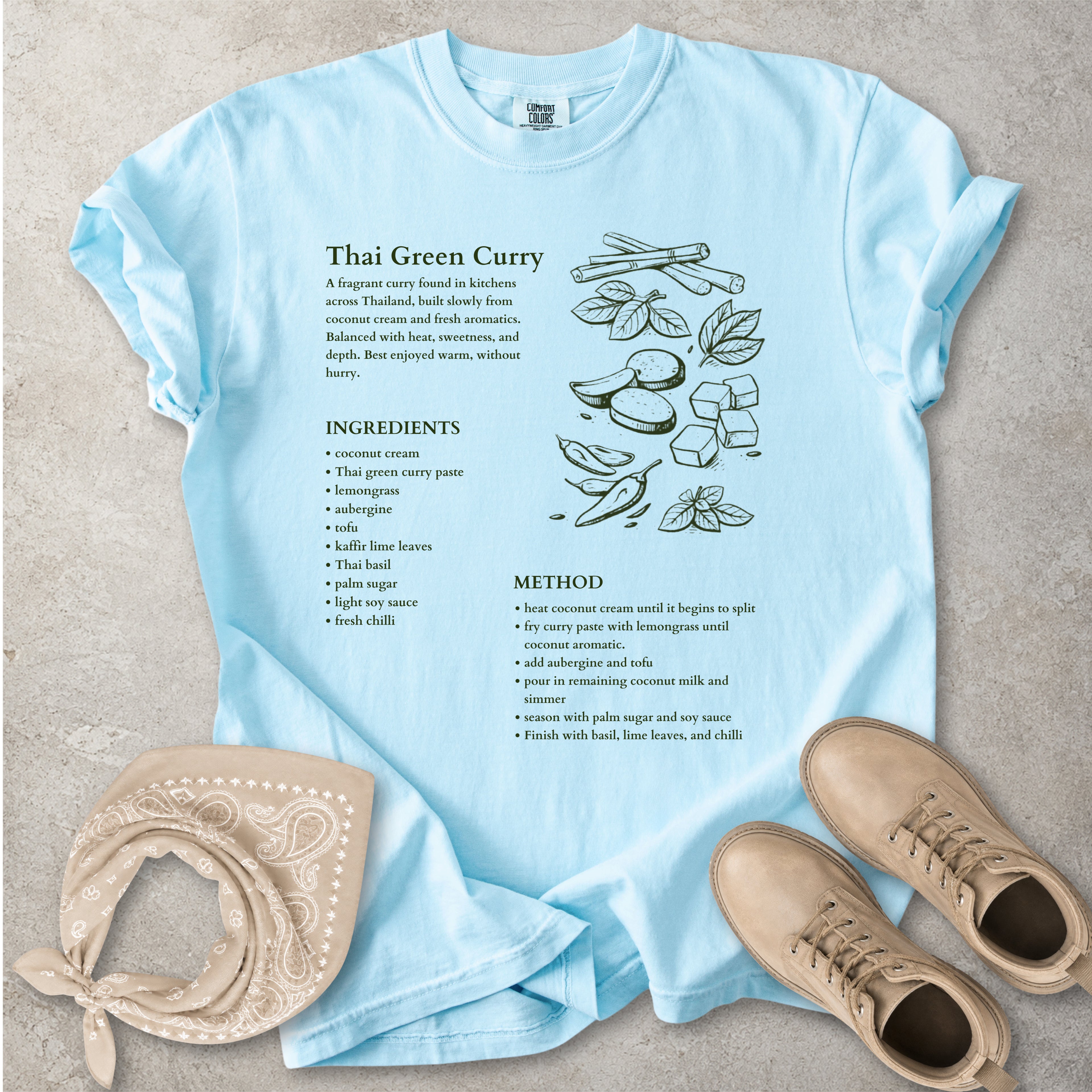 Light blue Comfort Colors graphic T-shirt with Thai green curry recipe text, ingredients list, method and food illustration, styled with tan bandana and boots