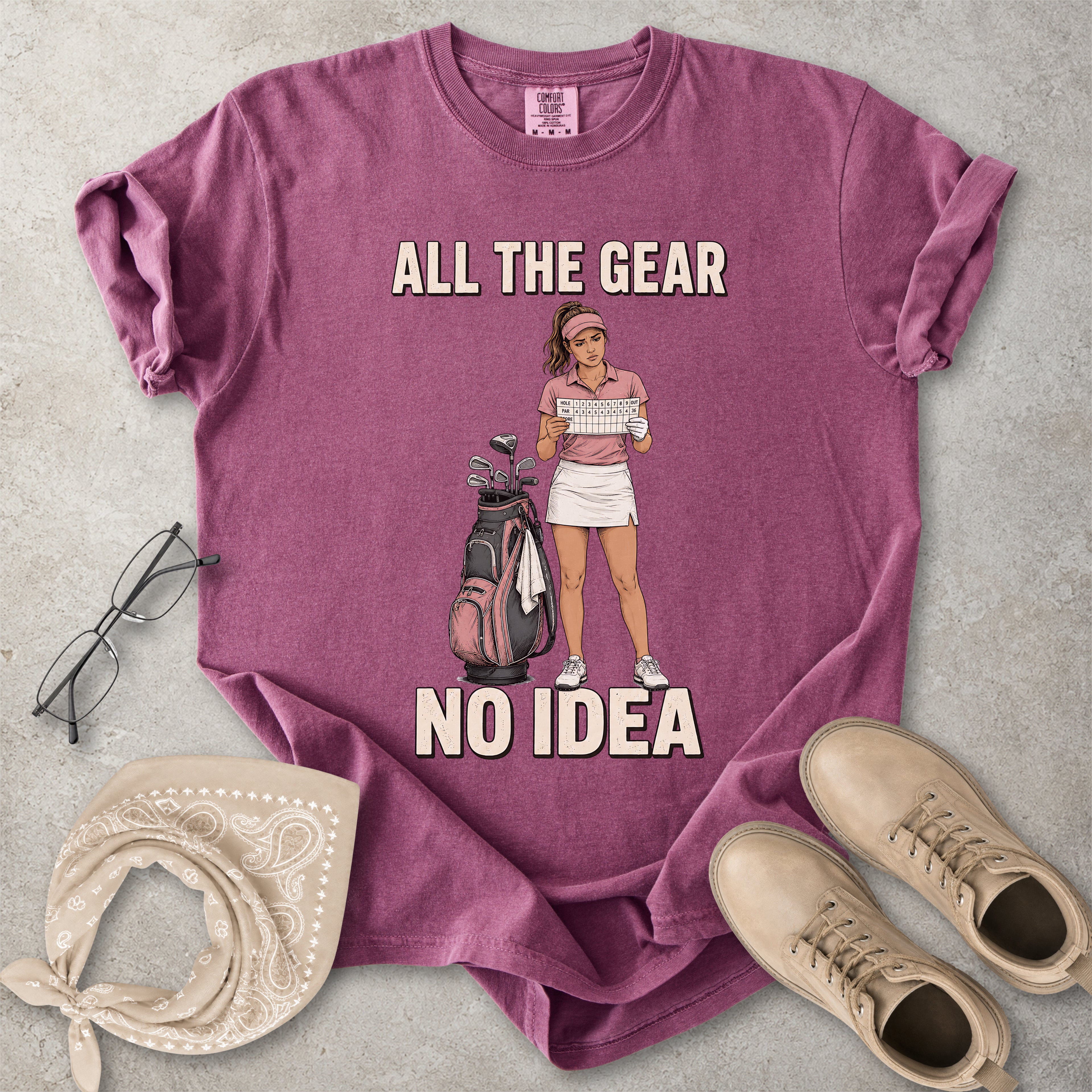 Berry Comfort Colors 1717 T-shirt with a funny All the Gear No Idea golf graphic showing a woman golfer holding a scorecard beside a golf bag.